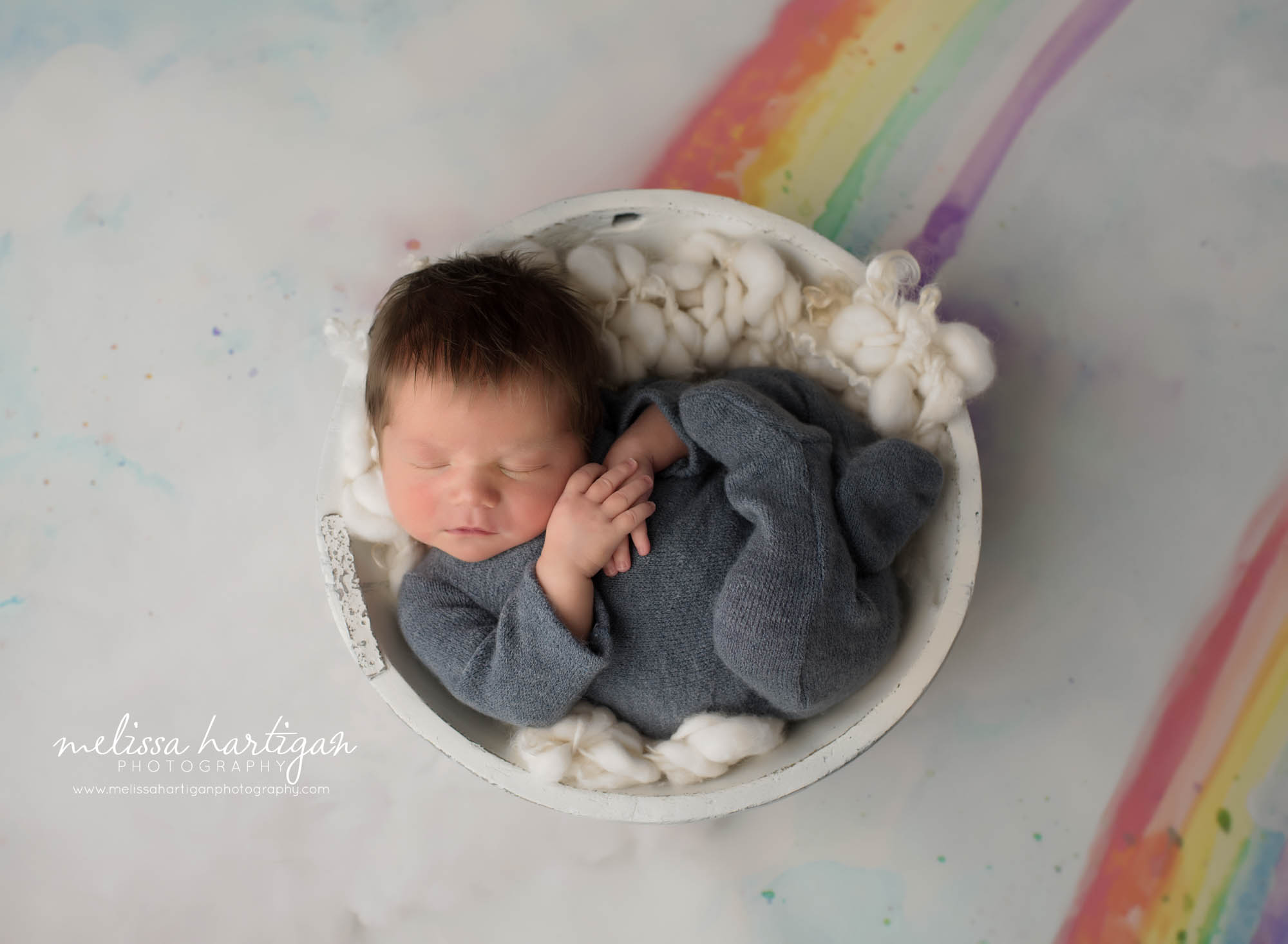 baby boy wearing footed sleeper posed in cream wooden bowl rainbow baby set up newborn photography CT