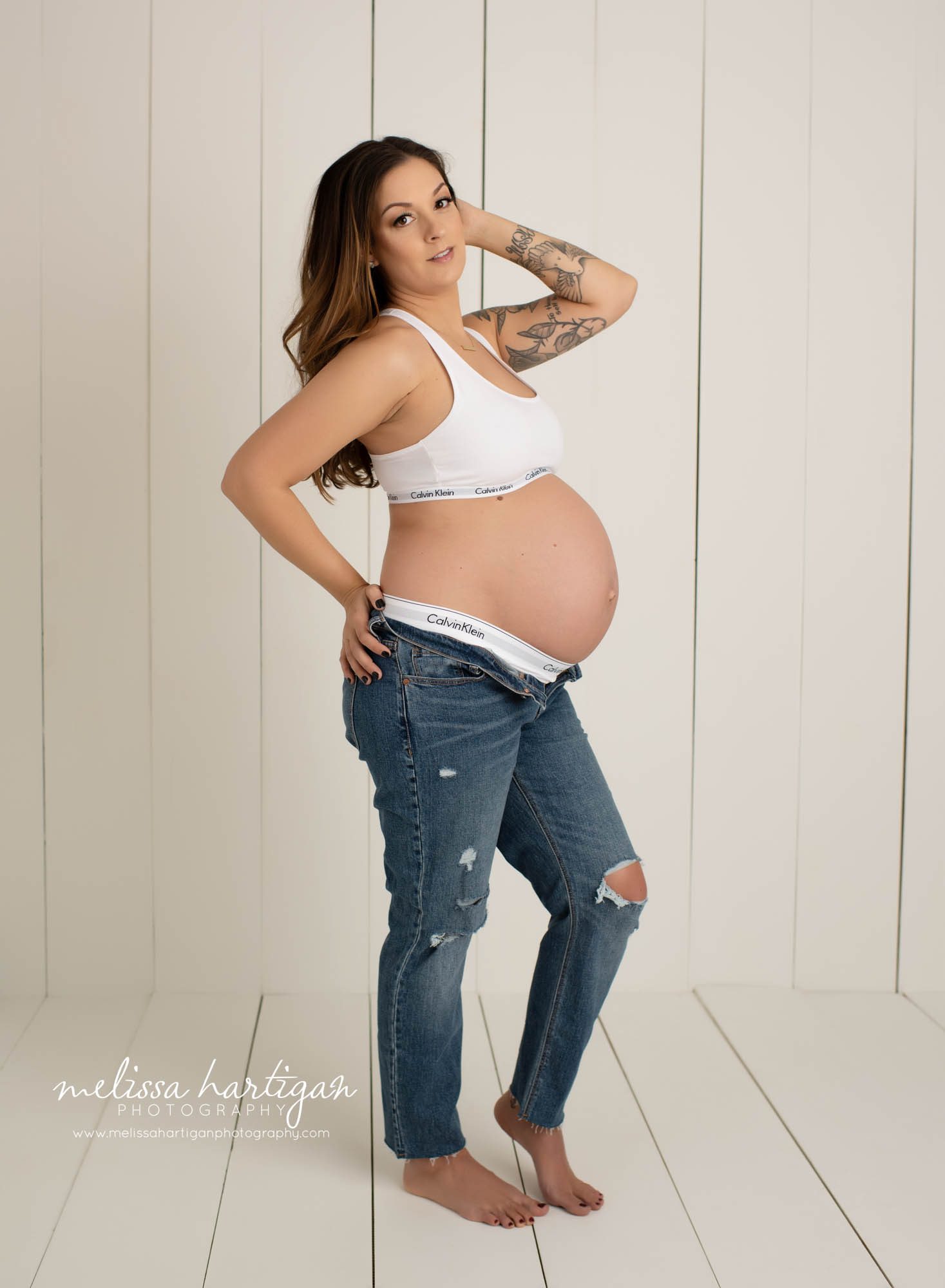 standing maternity photography pose mama wearing jeans unbuttoned wearing calvin klein sports bar and short set CT maternity Photographer