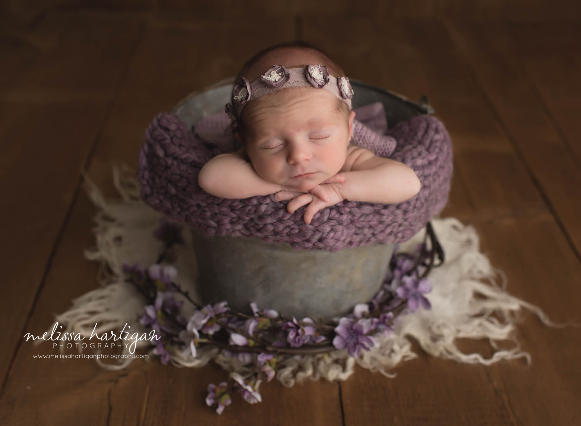 newborn baby girl posed in metal bucket with purple knit layer and purple flower headband CT newborn photography