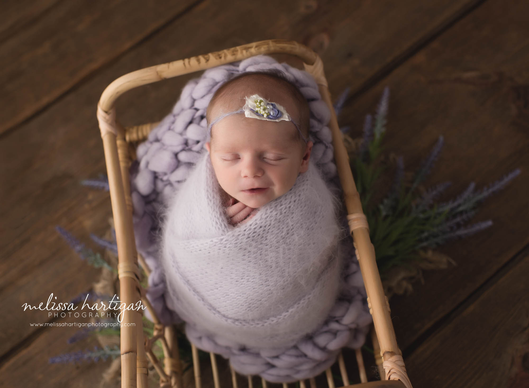 newborn baby girl wrapped in light purple knitted wrap with tieback posed in basket