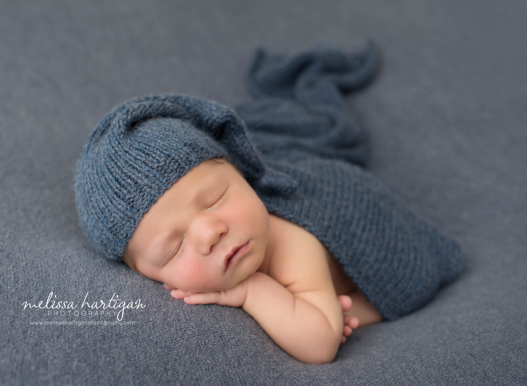 newborn baby boy posed modified taco pose newborn photography with blue sleepy back and knit layer draped over his back newborn Photography Glastonbury CT
