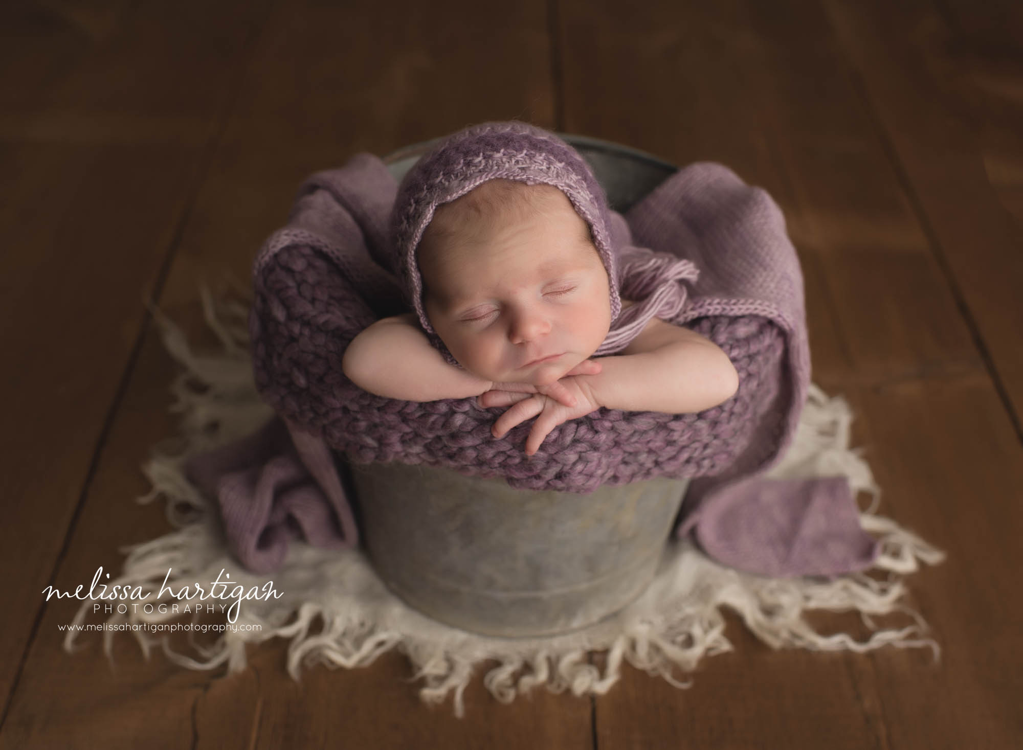 newborn baby girl posed in bucket with purple knitted bonnet newborn photography CT