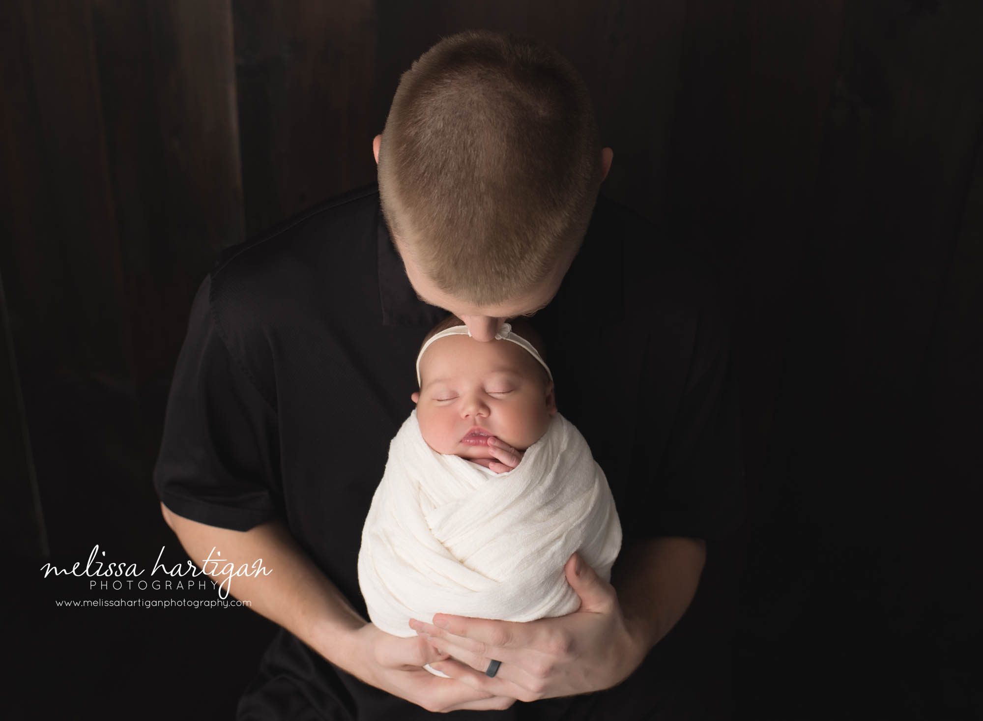 dad kissing the top of baby daughters head in dad and newborn pose baby photography session