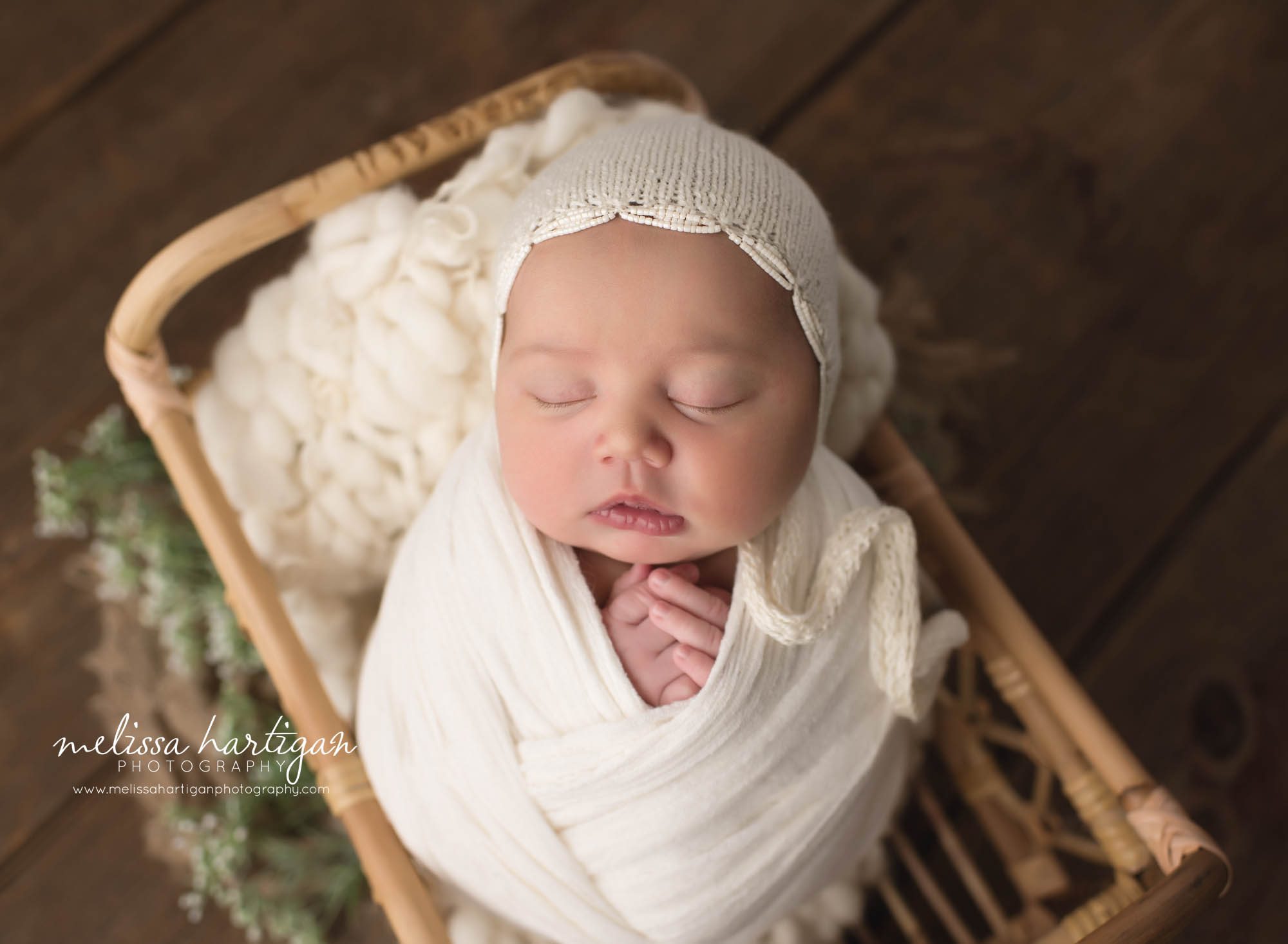 newborn baby girl wrapped in cream wrap with cream knitted bonnet posed in basket with babys breath floral element CT newborn Photographer