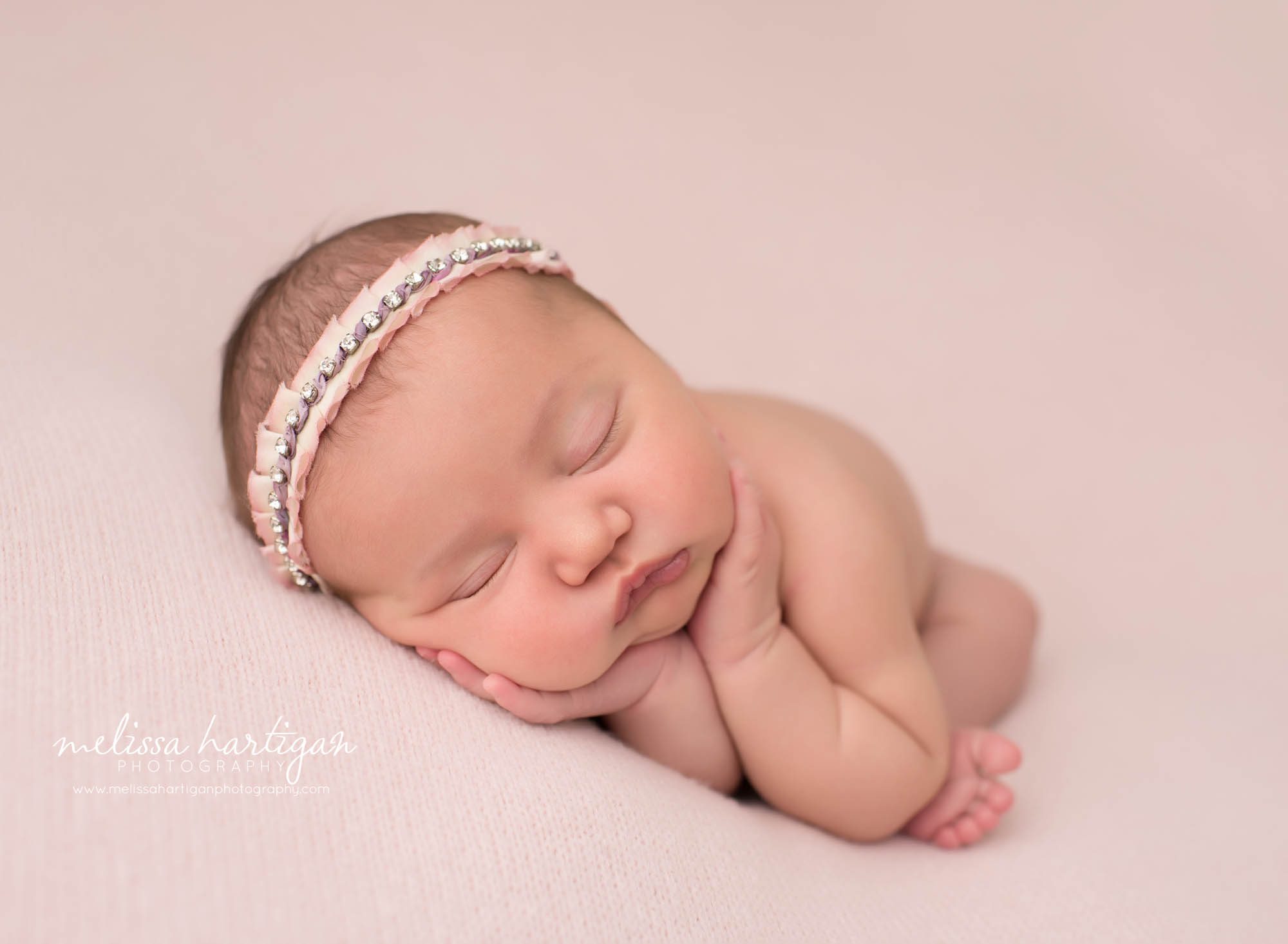 newborn baby girl posed on side with headband new london county baby photographer