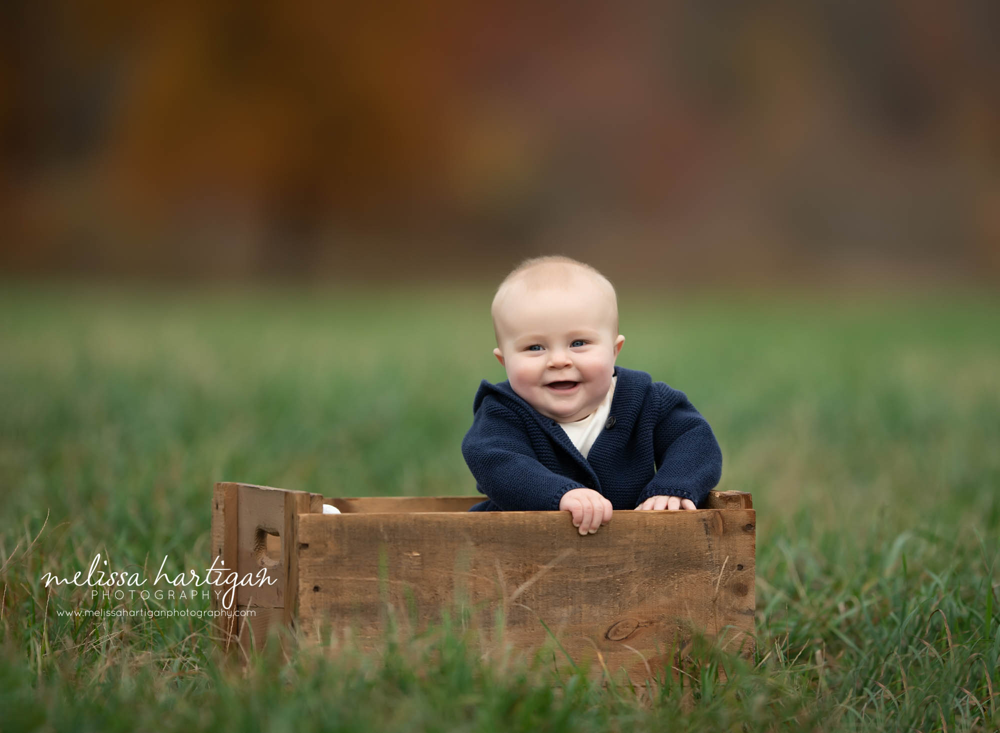 baby boy sitting in wooden crate in field