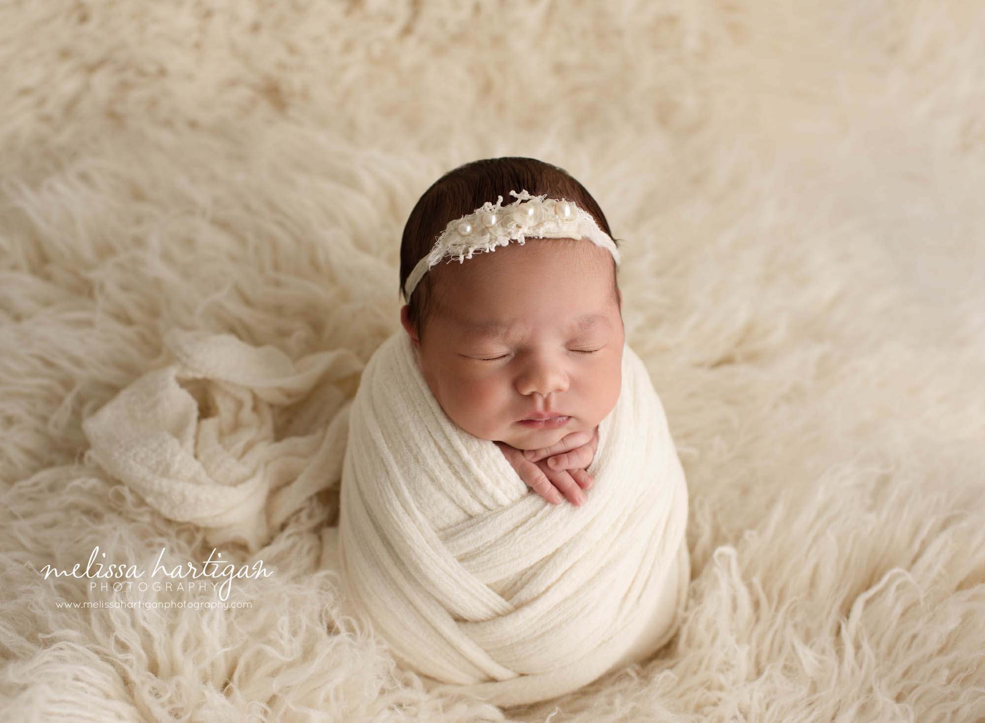 newborn baby girl wrapped in cream wrap posed potato pose