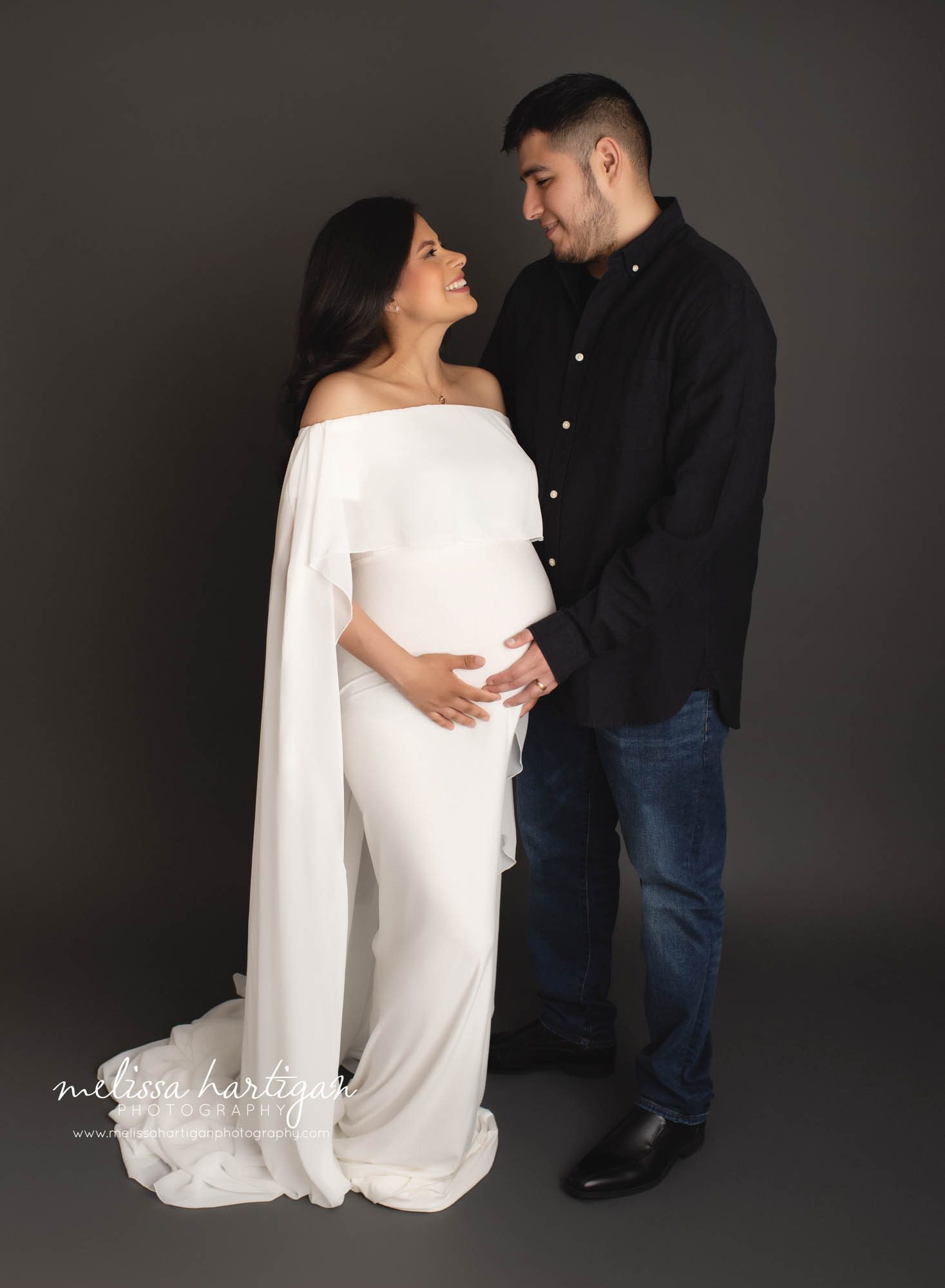 couple smiling holding baby belly in studio maternity photography CT