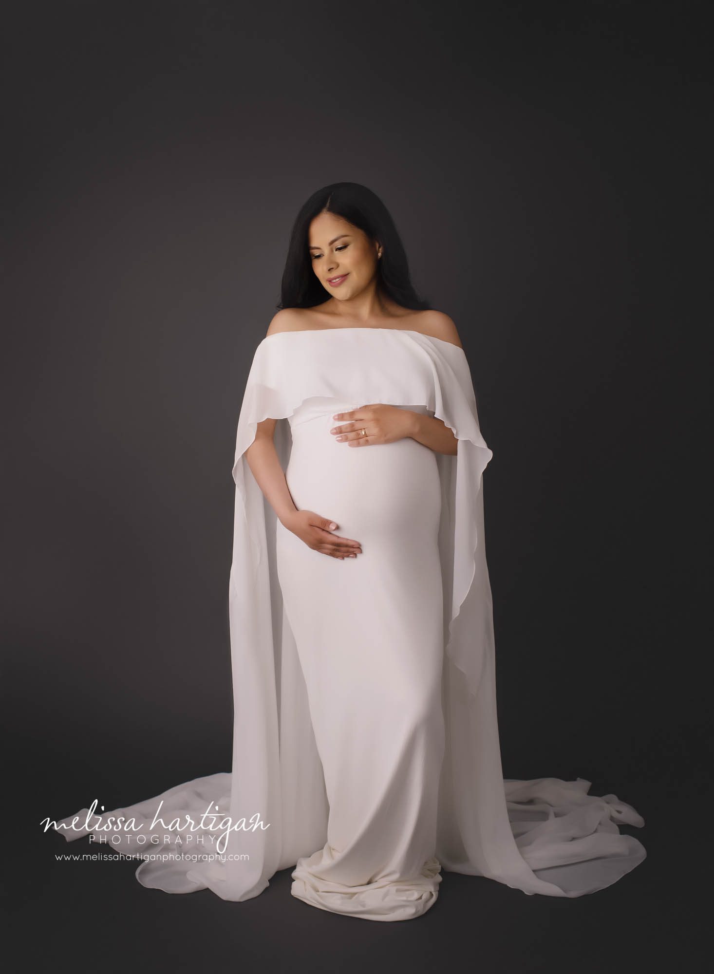 pregnant mama wearing long white maternity gown with long white sleeves studio maternity session CT maternity Photographer