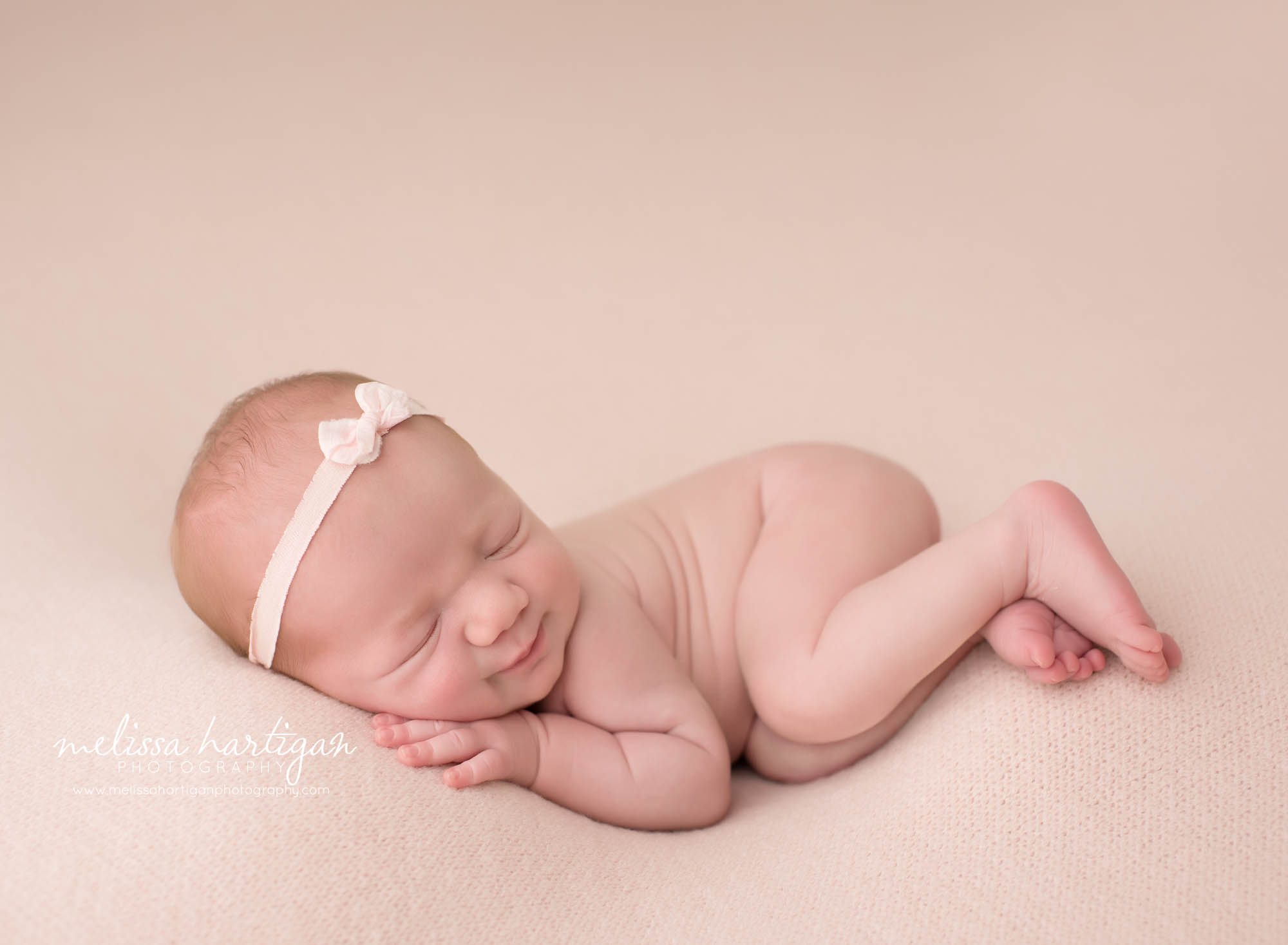 newborn baby girl posed on side wearing light pink bow headband tolland county CT newborn photographer