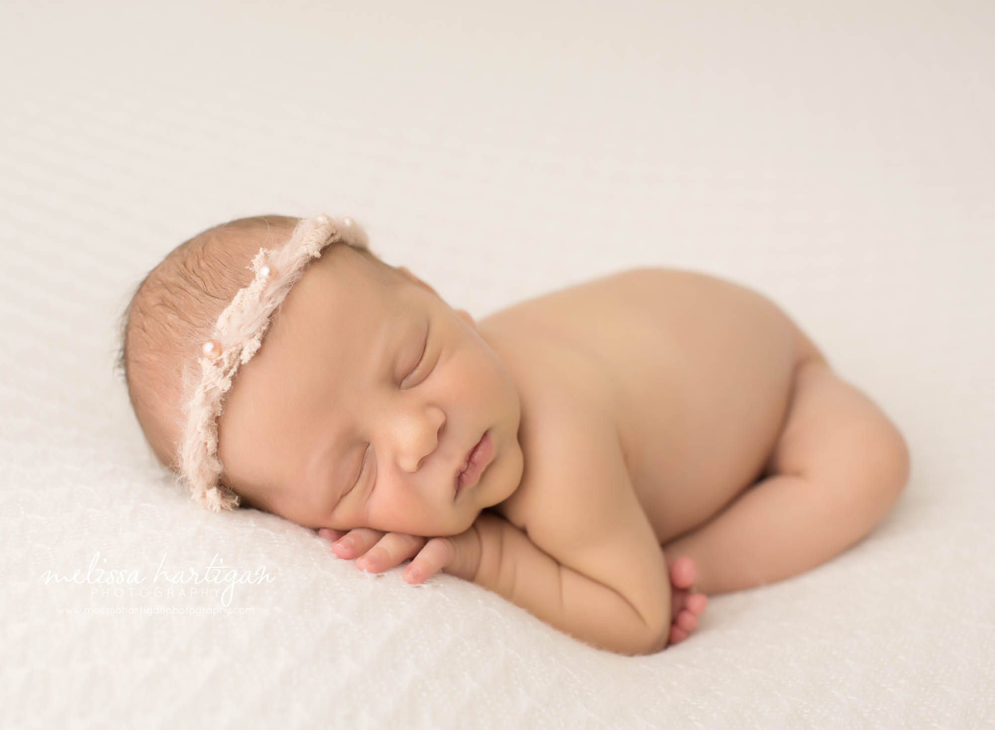 baby girl posed on tummy wearing light pink headband with pearls