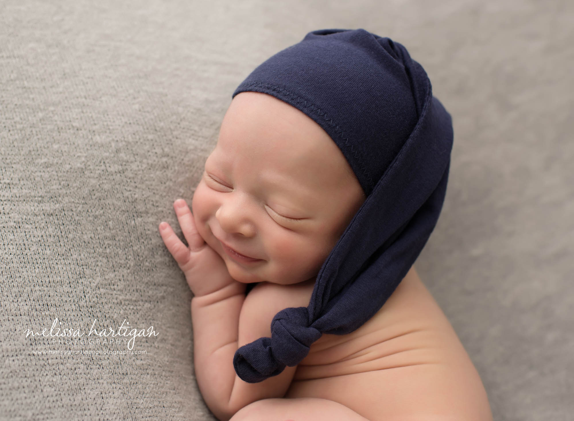newborn baby boy smiling smirking with navy blue sleepy cap middletown ct newborn photography