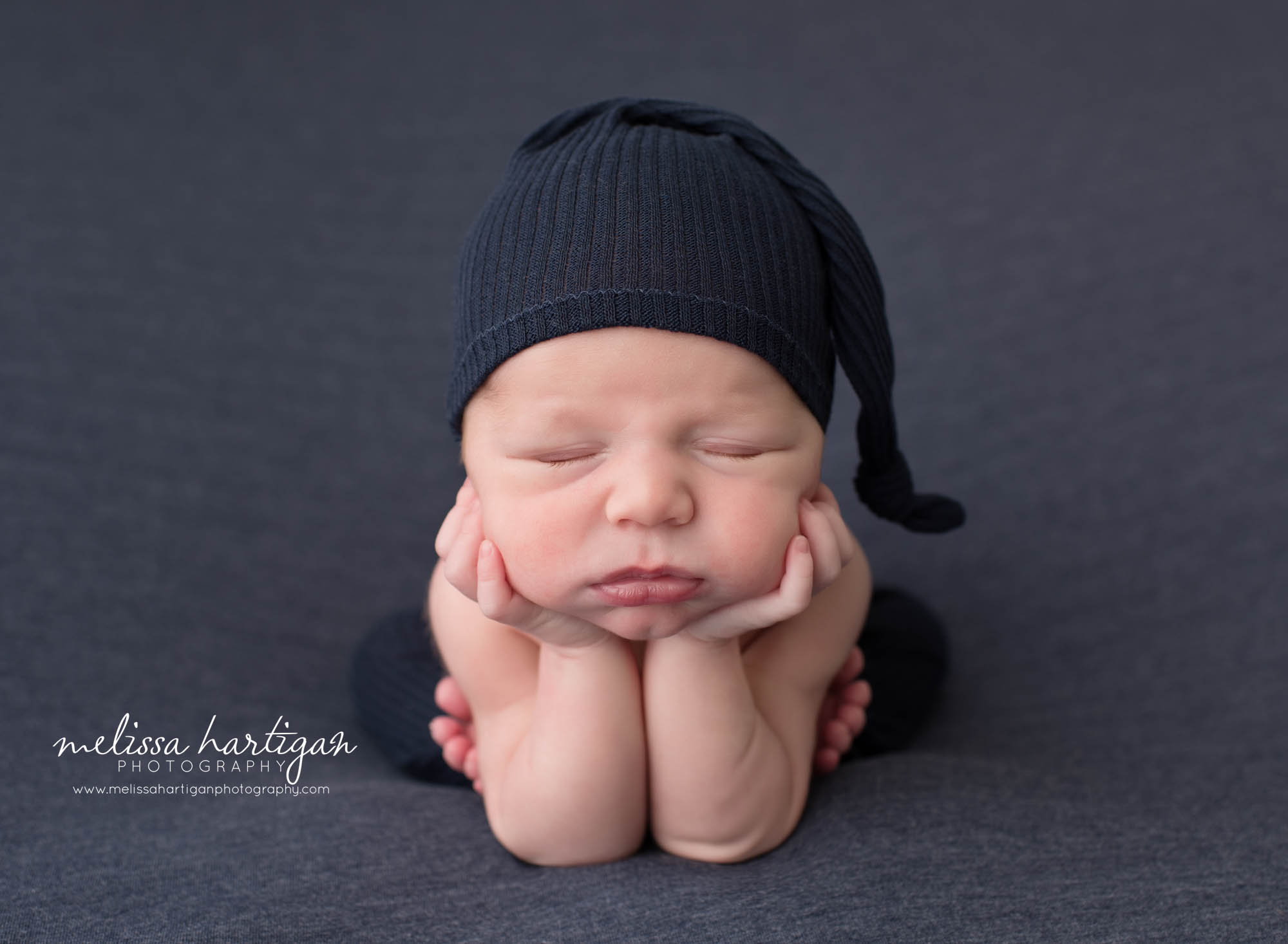 newborn baby goy posed froggy pose wearing navy blue sleepy cap Newborn Photography Middlesex county CT studio