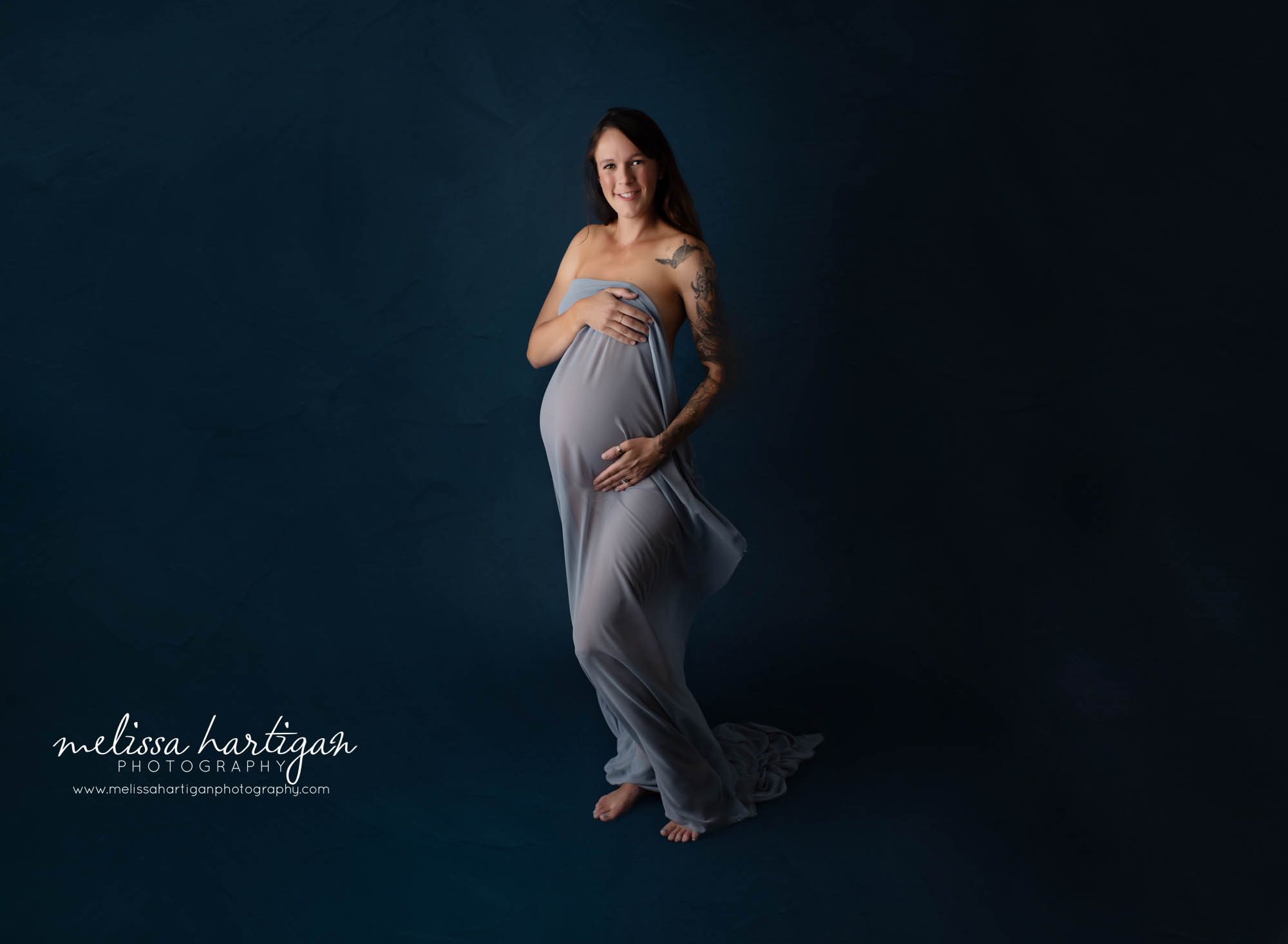 pregnant mom smiling wearing draped fabric studio maternity