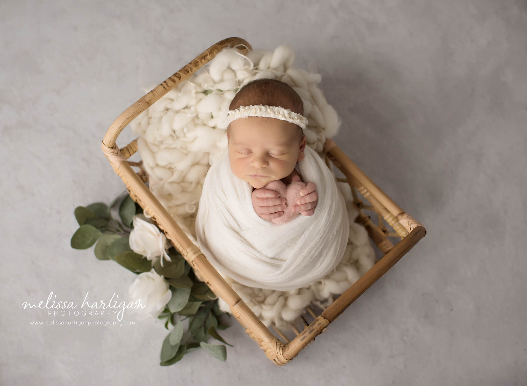 newborn baby girl wrapped in ivory wrap holding pink felted heart prop