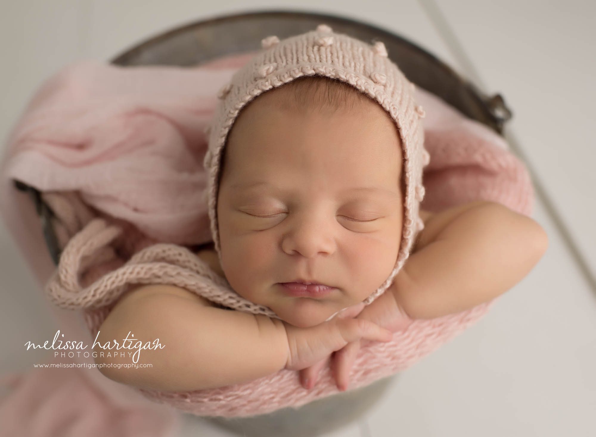 newborn baby girl posed in bucket wear pink bonnet