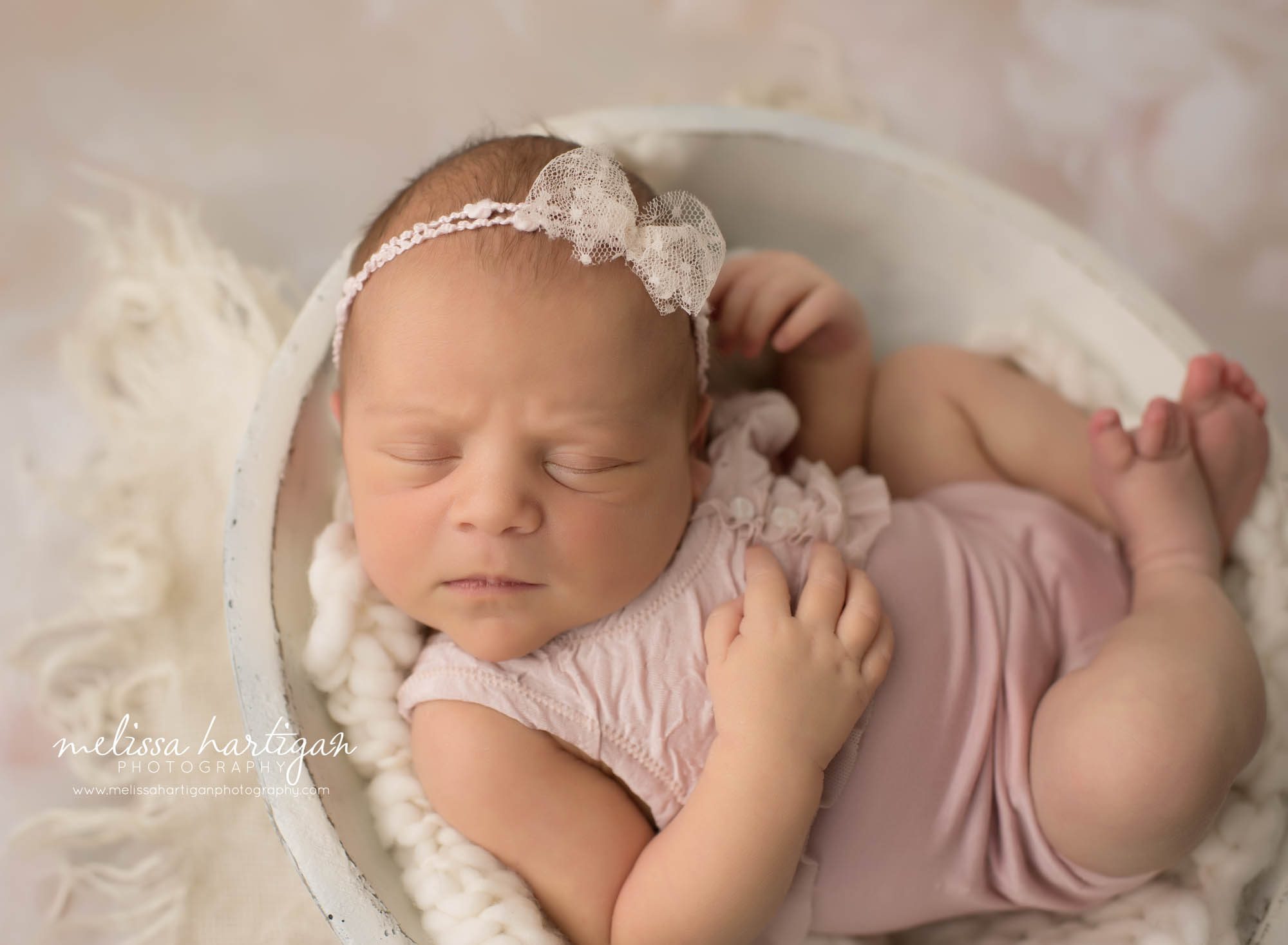 newborn baby girl posed in wooden bowl wearing pink outfit and bow lace headband windsor CT newborn photography