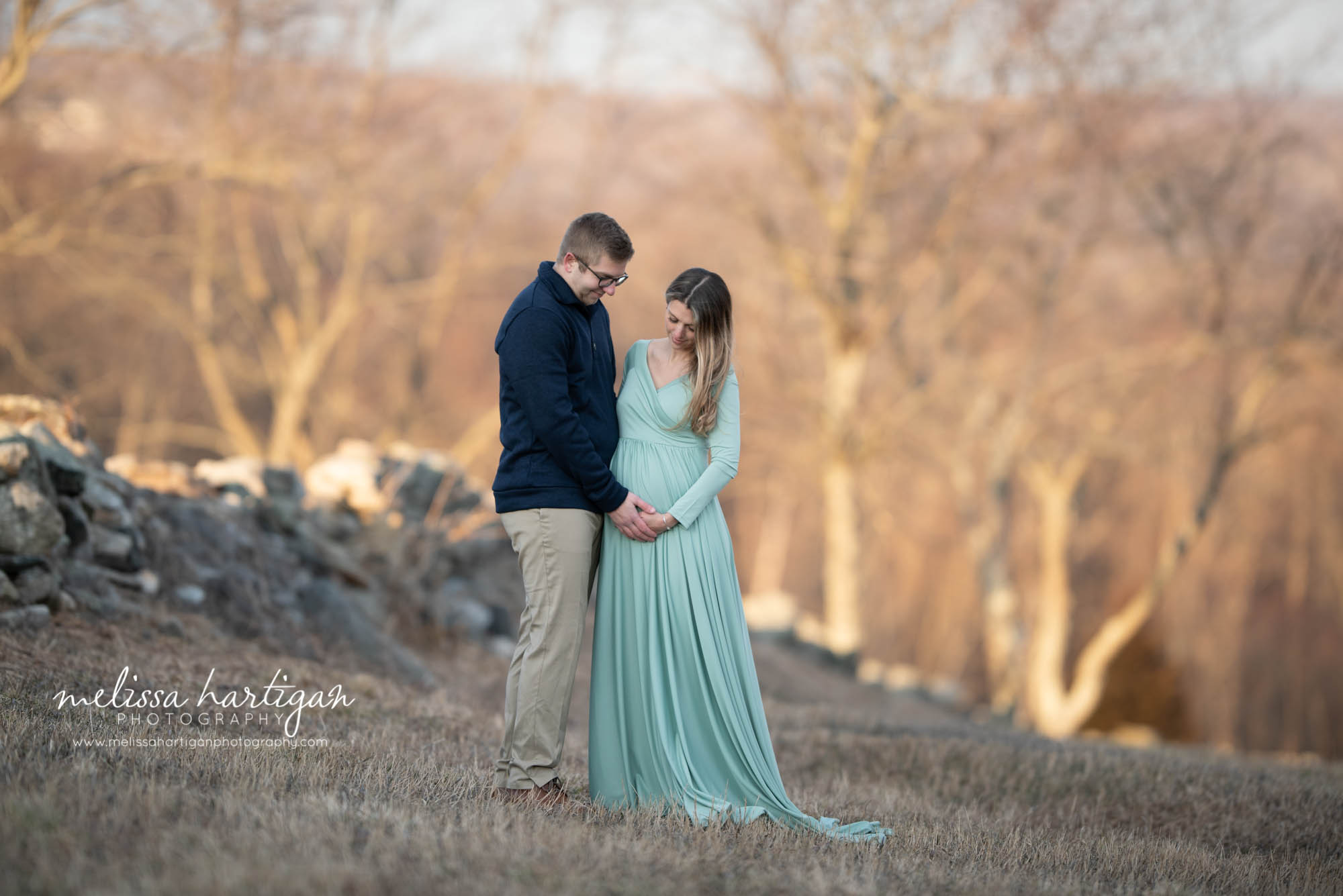 couple holding baby bump mom wearing long sleeved long maternity dress Danielson Maternity Photography