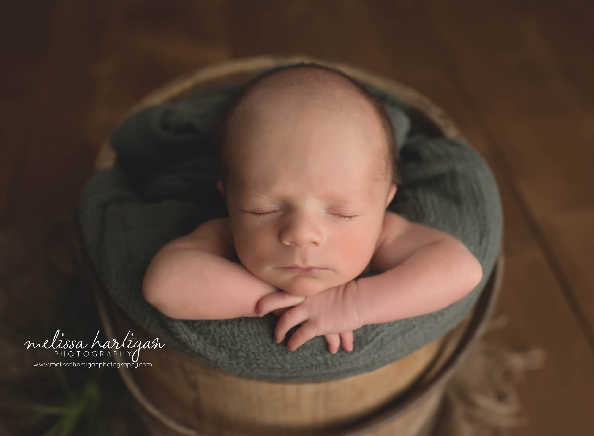 newborn baby boy posed in wooden bucket with green layer Connecticut newborn photography