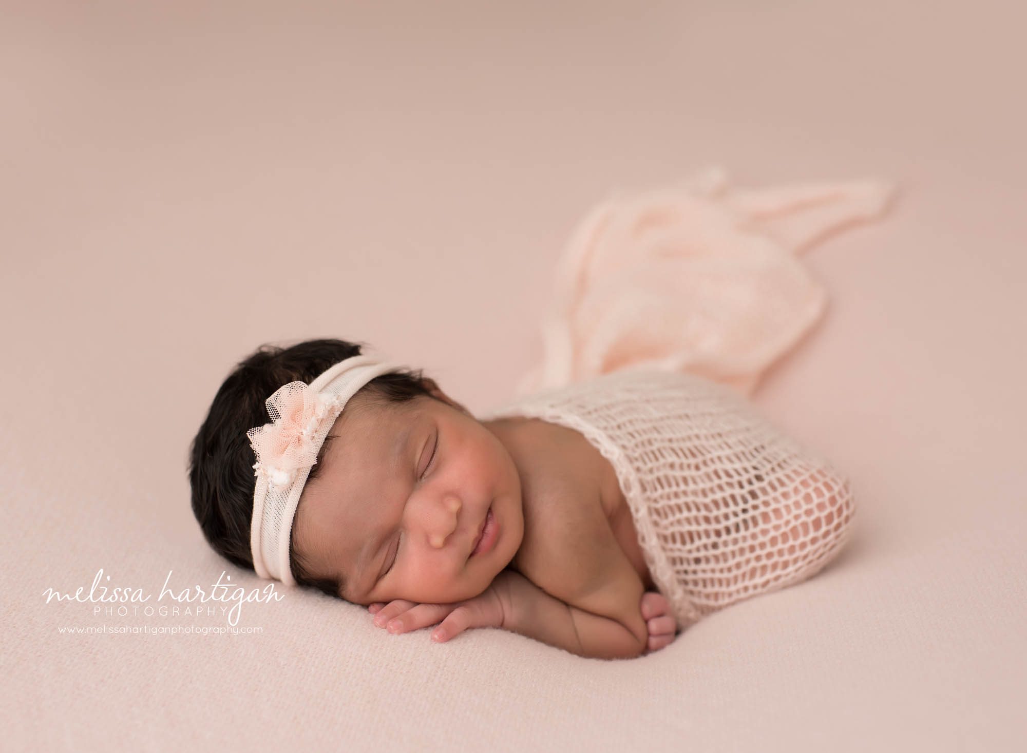 newborn baby girl posed on light pink backdrop with pink tulle bow headband hamden CT newborn Photography
