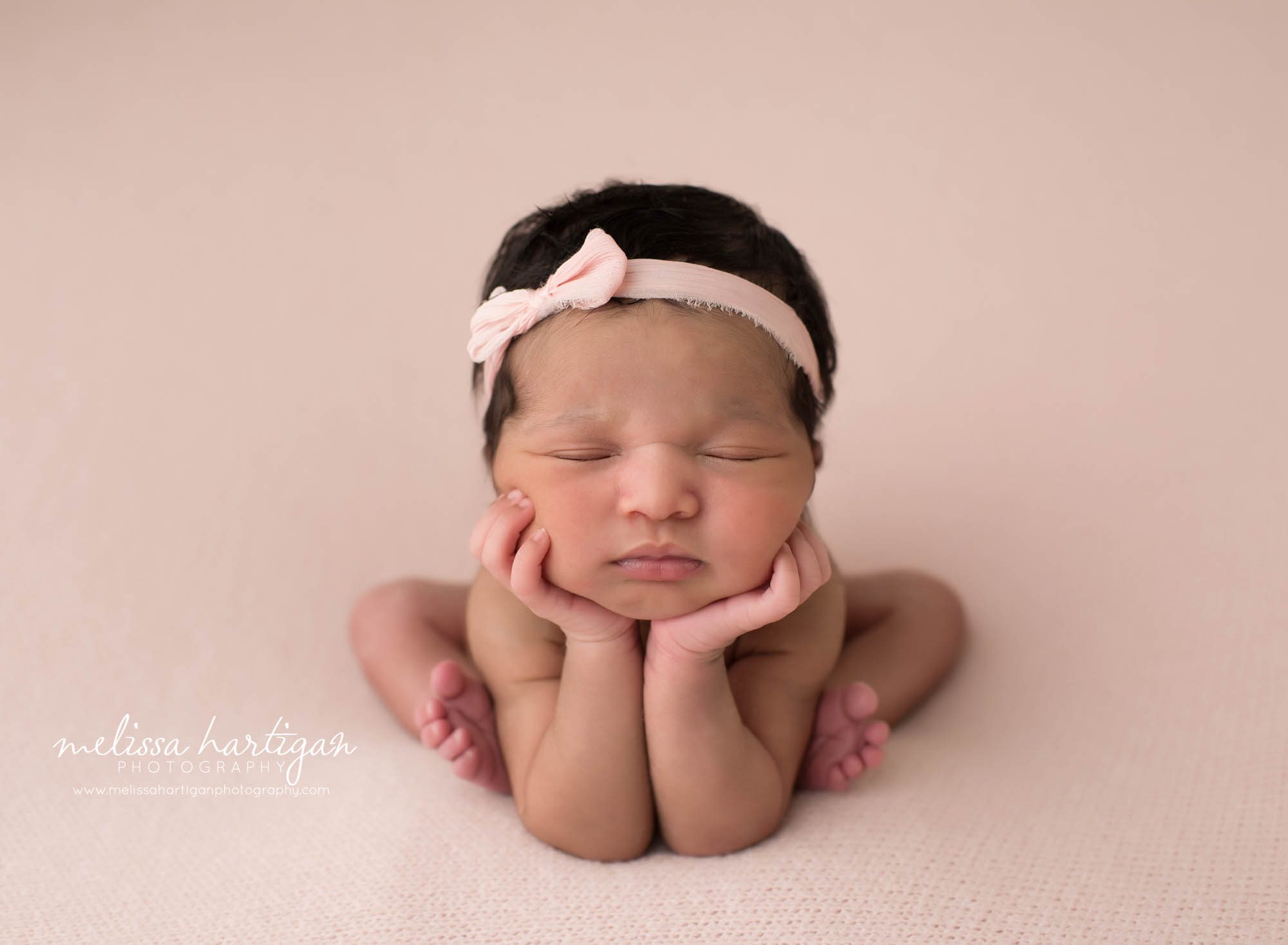newborn baby girl posed froggy pose wearing pink bow headband