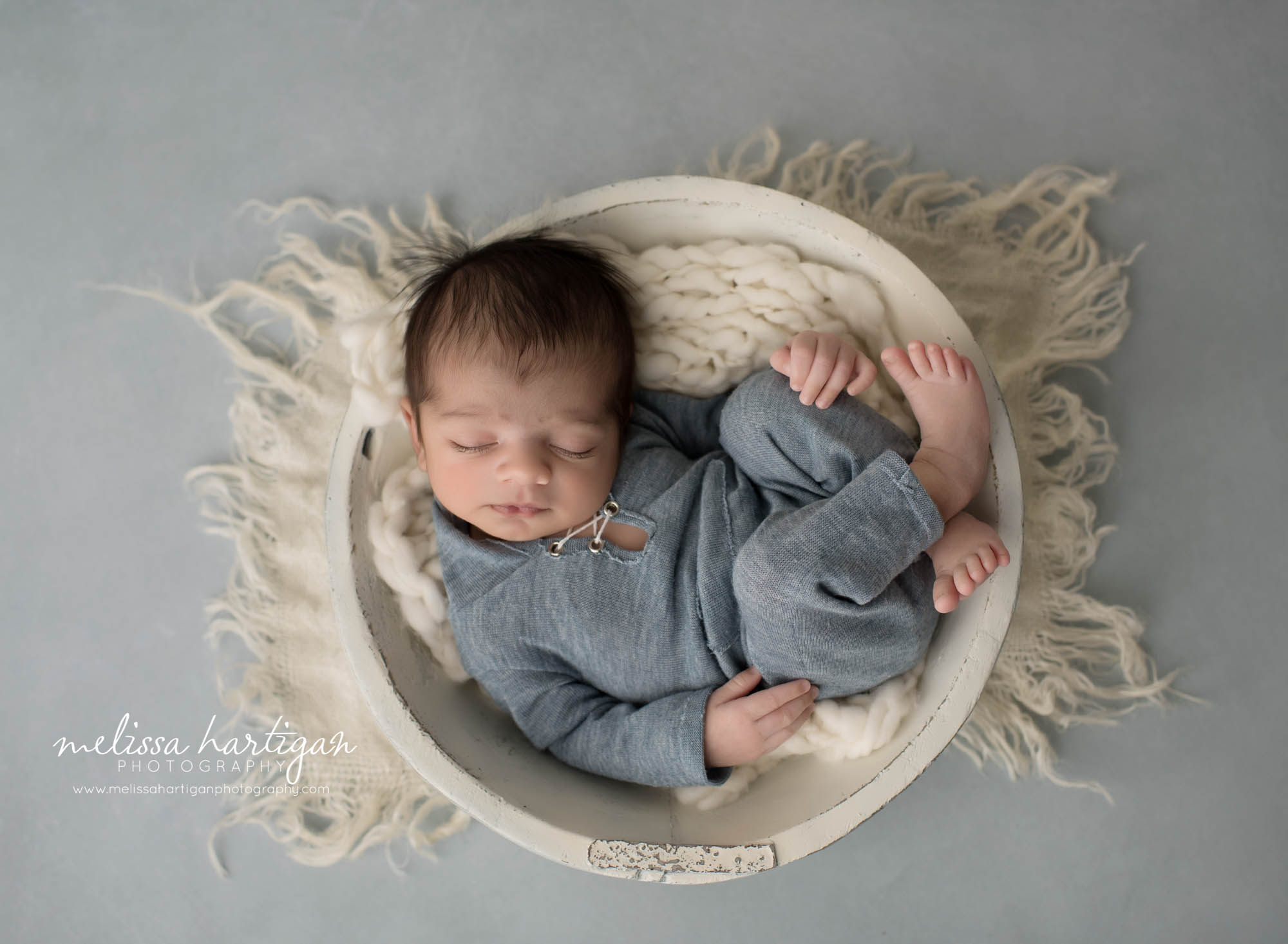 newborn baby boy wearing blue outfit posed in wooden cream bowl CT newborn Photography Manchester