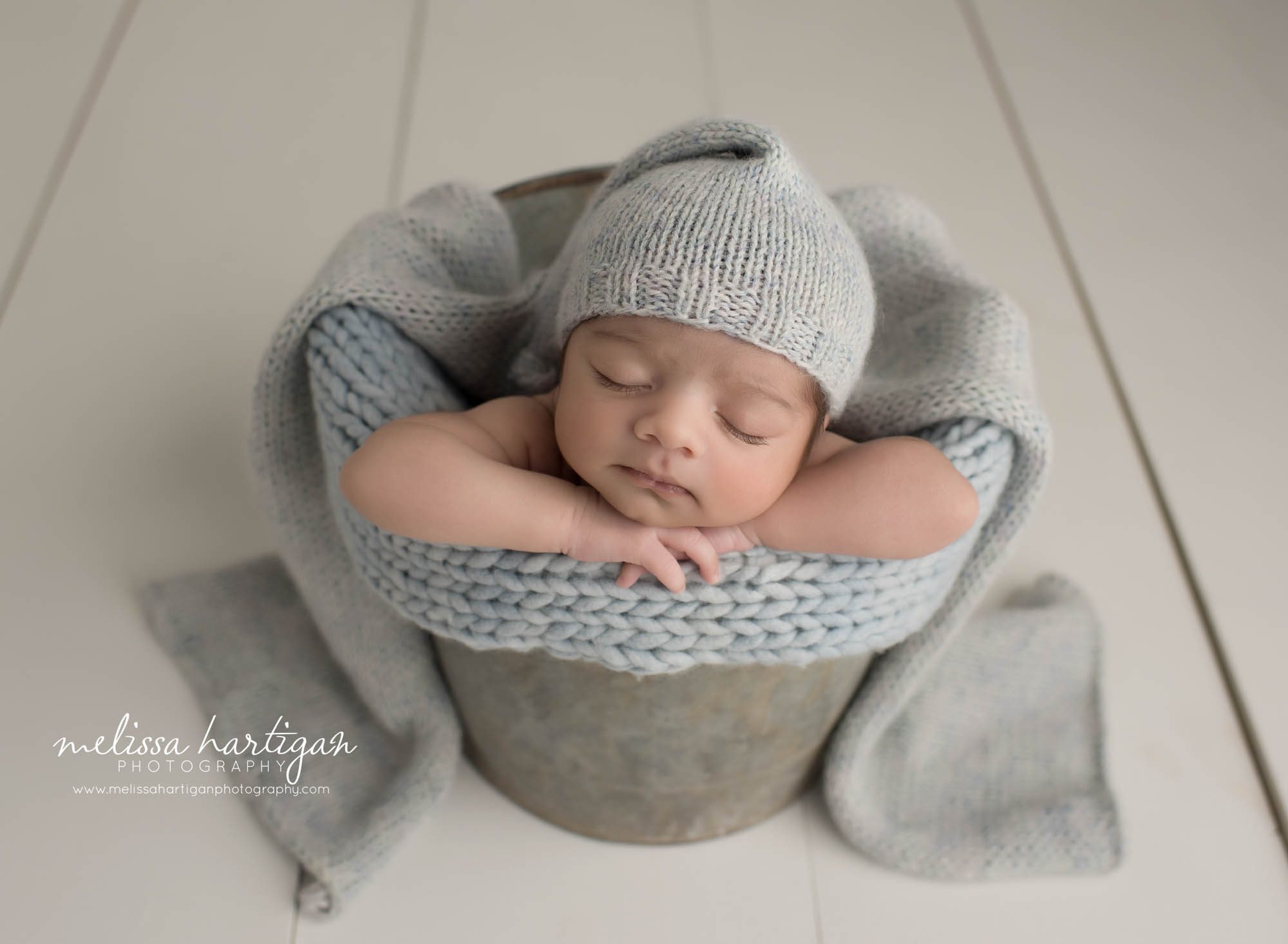 newborn baby boy posed in metal bucket wearing light blue knitted sleepy cap manchester CT newborn Photography