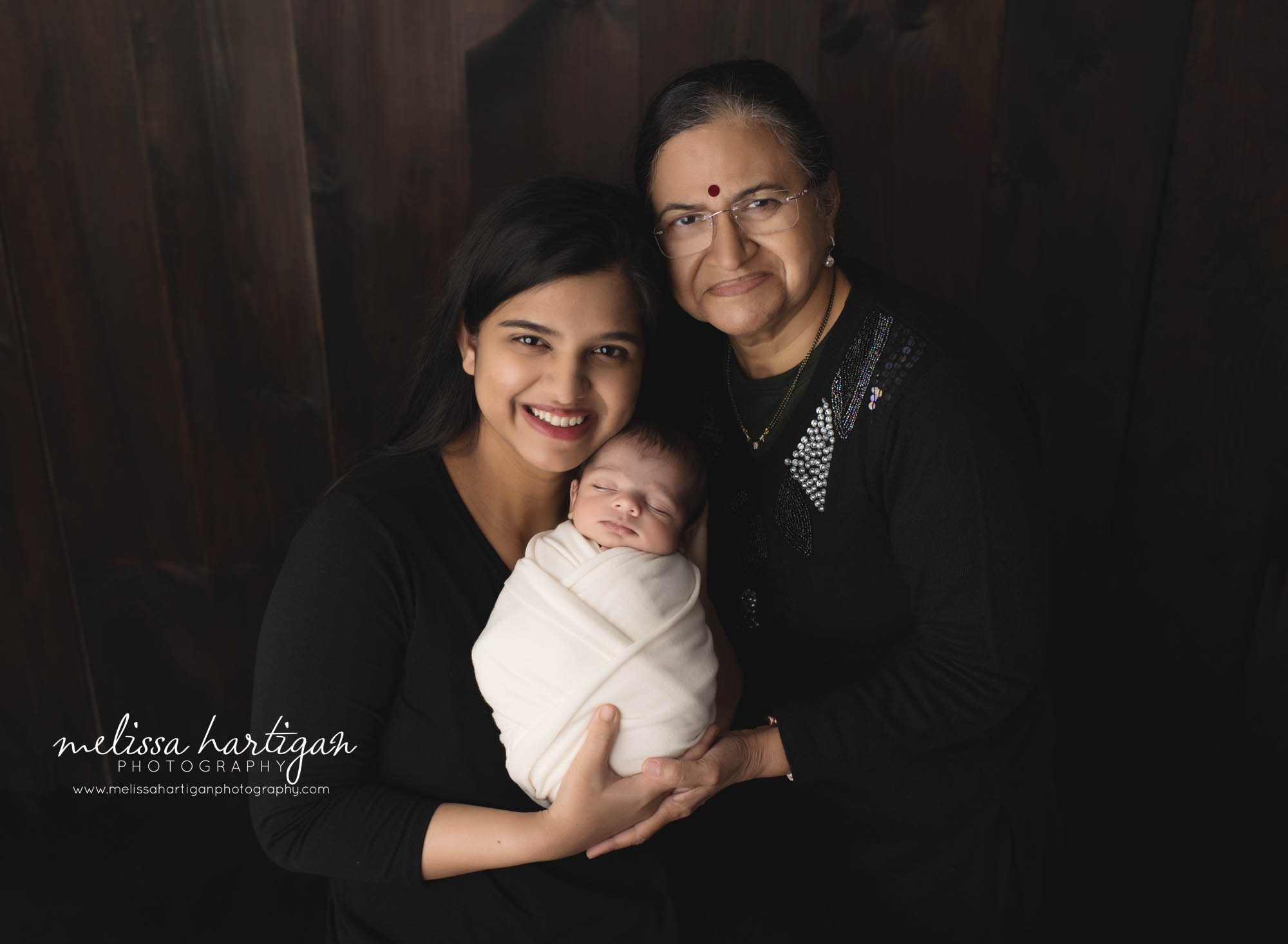 mom holding newborn son with baby's grandmother family pose newborn photography session