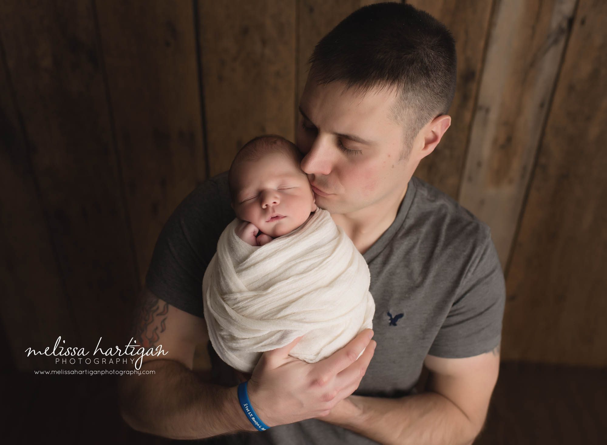 dad holding wrapped newborn son kissing him on the cheek newborn photography tolland CT