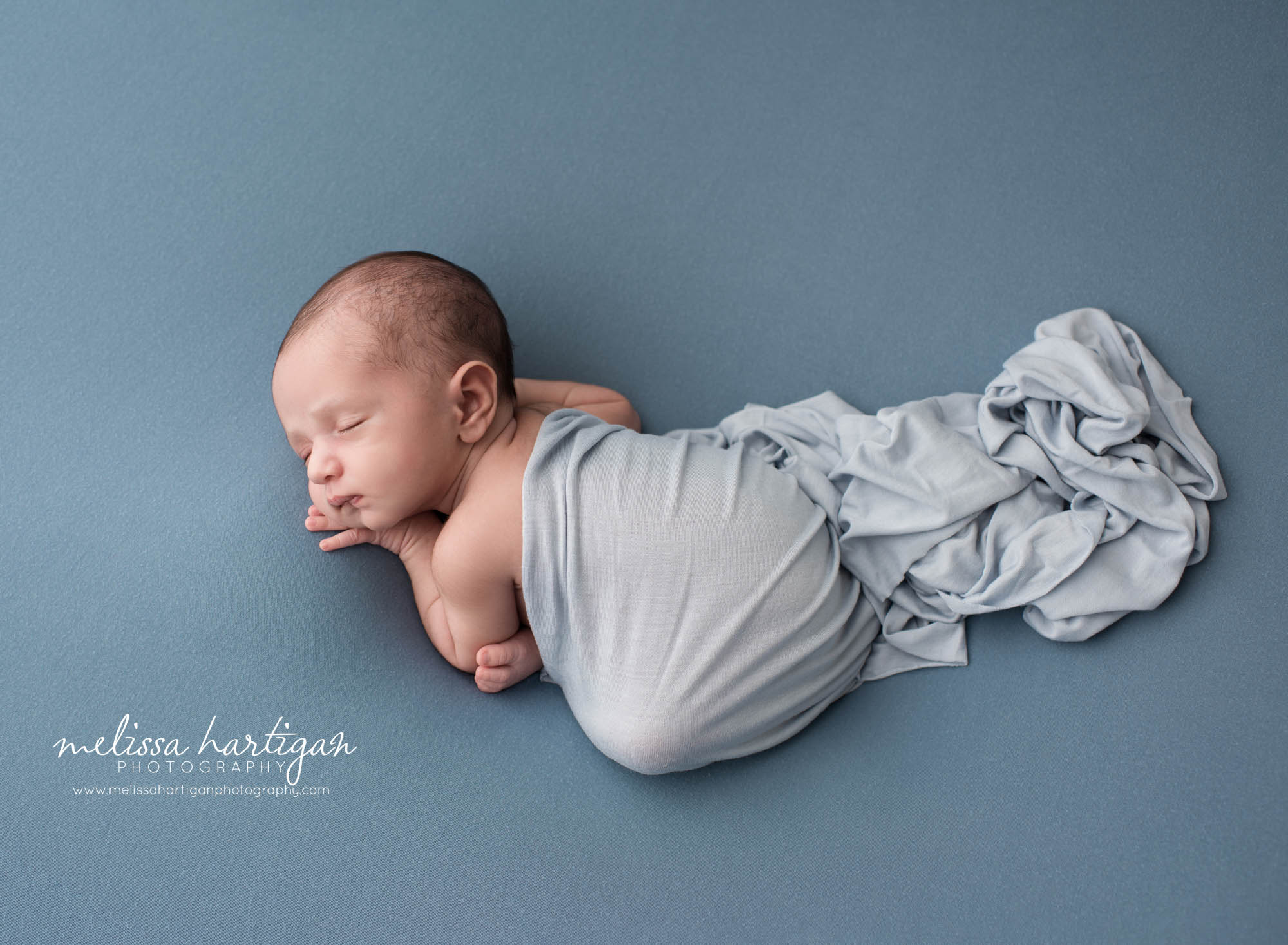 newborn baby boy posed on tummy with blue layer wrap draped over Newborn photography new haven