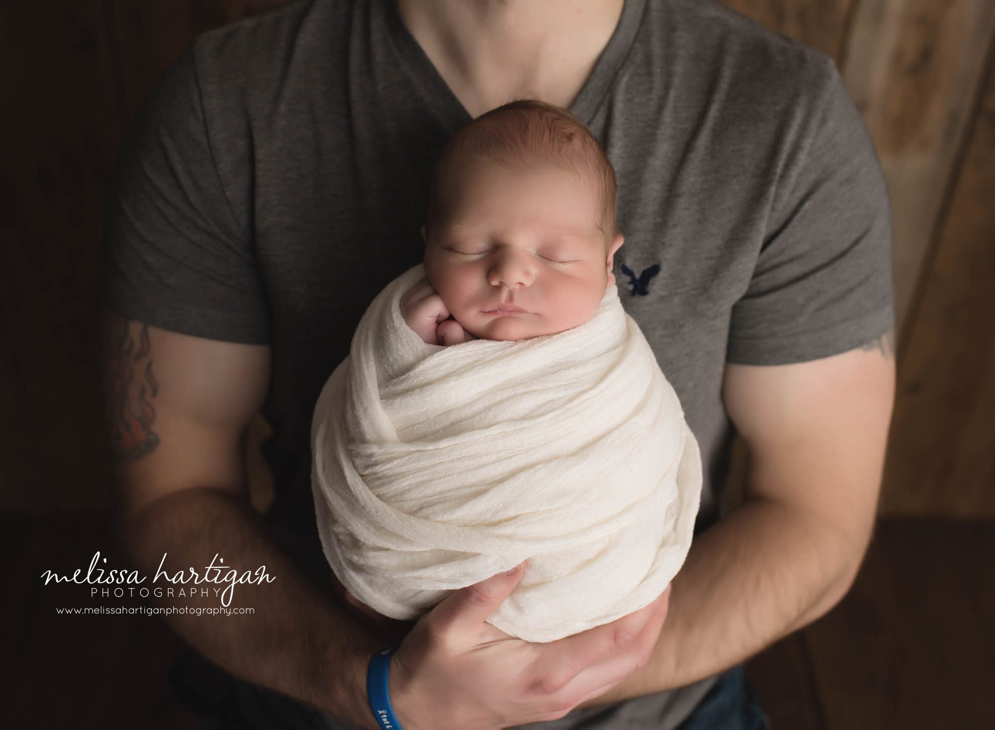 dad holding newborn son close up baby wrapped 