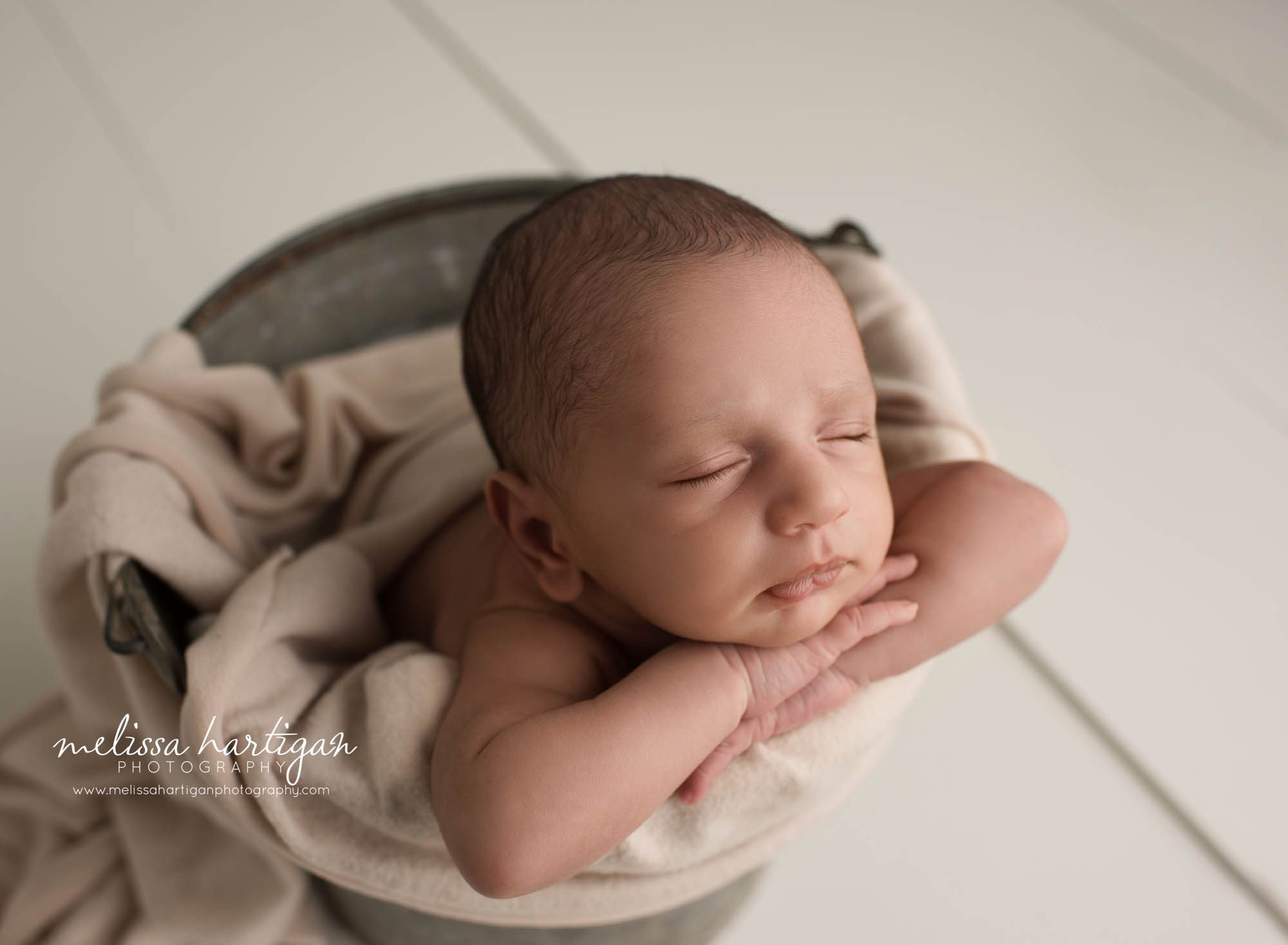 newborn baby boy posed in metal bucket with tan colored layer