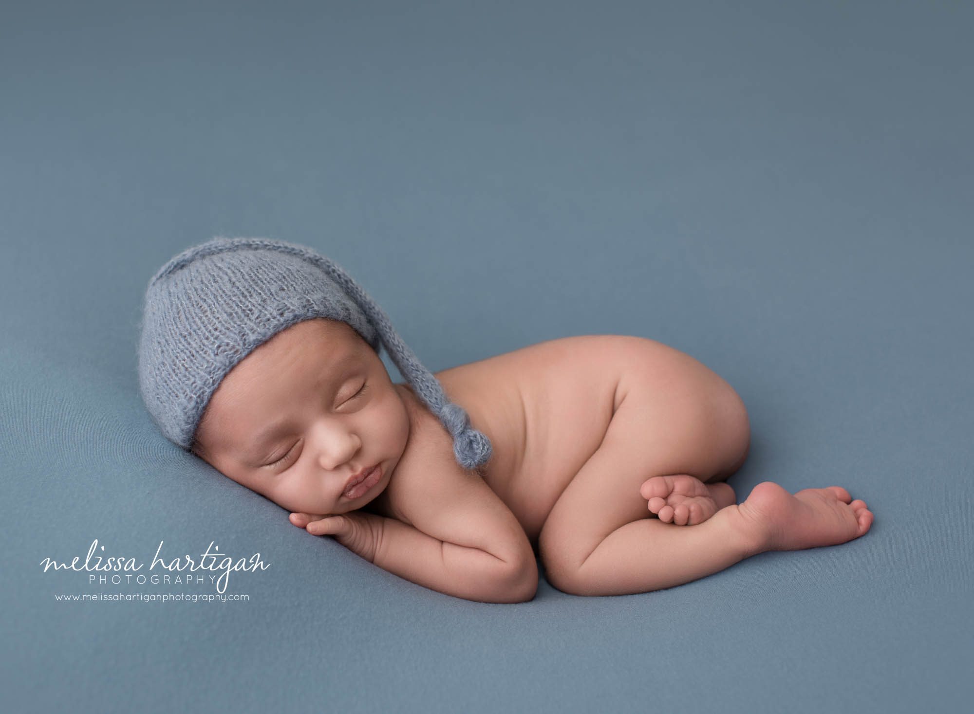 newborn baby boy pose don tummy wearing blue knitted sleepy cap New haven CT newborn photography