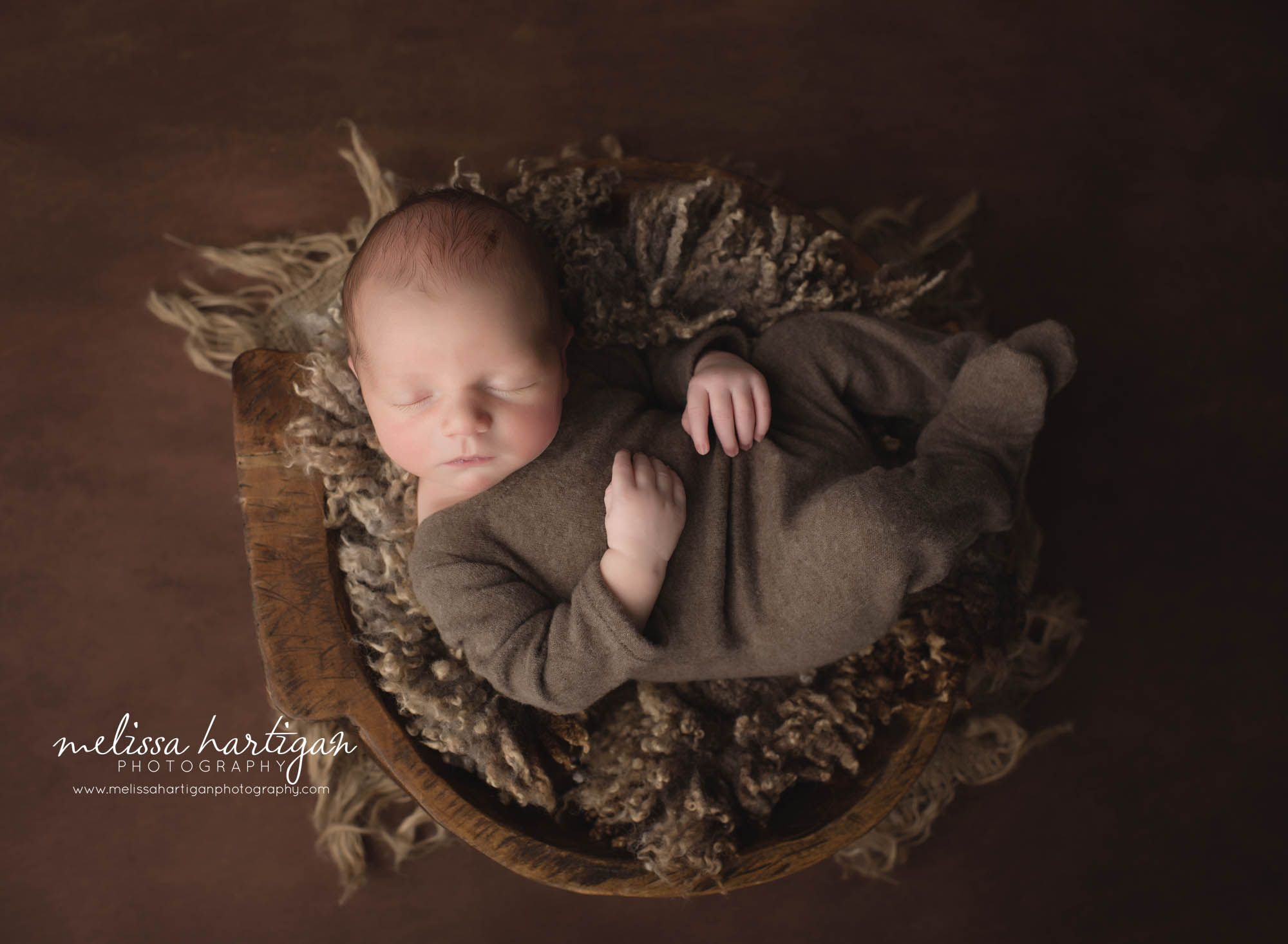 newborn baby boy wearing brown footed sleeper posed in wooden bowl tolland CT newborn Photography