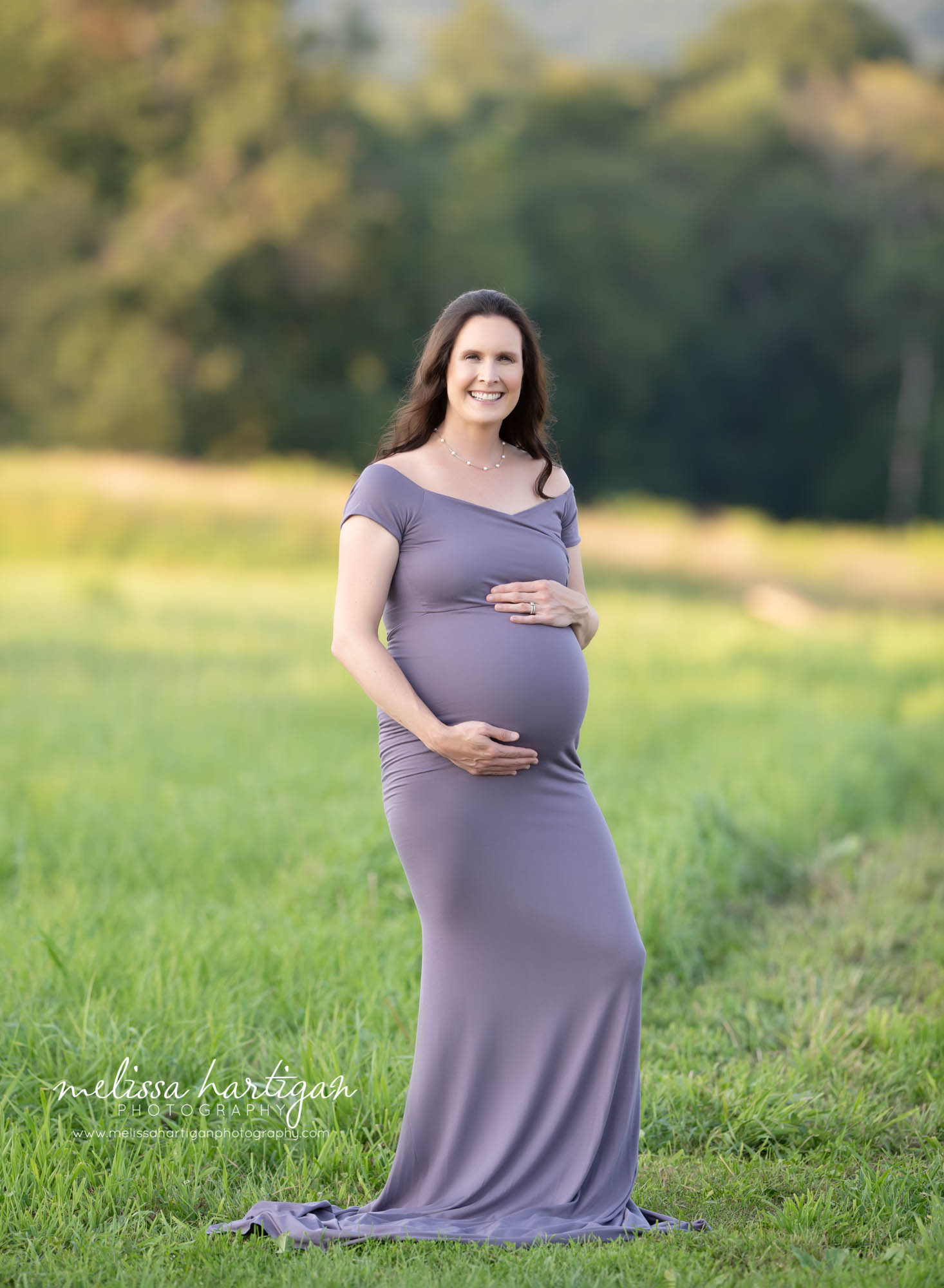 mom holding baby bump wearing long form fitting maternity dress maternity photographer CT