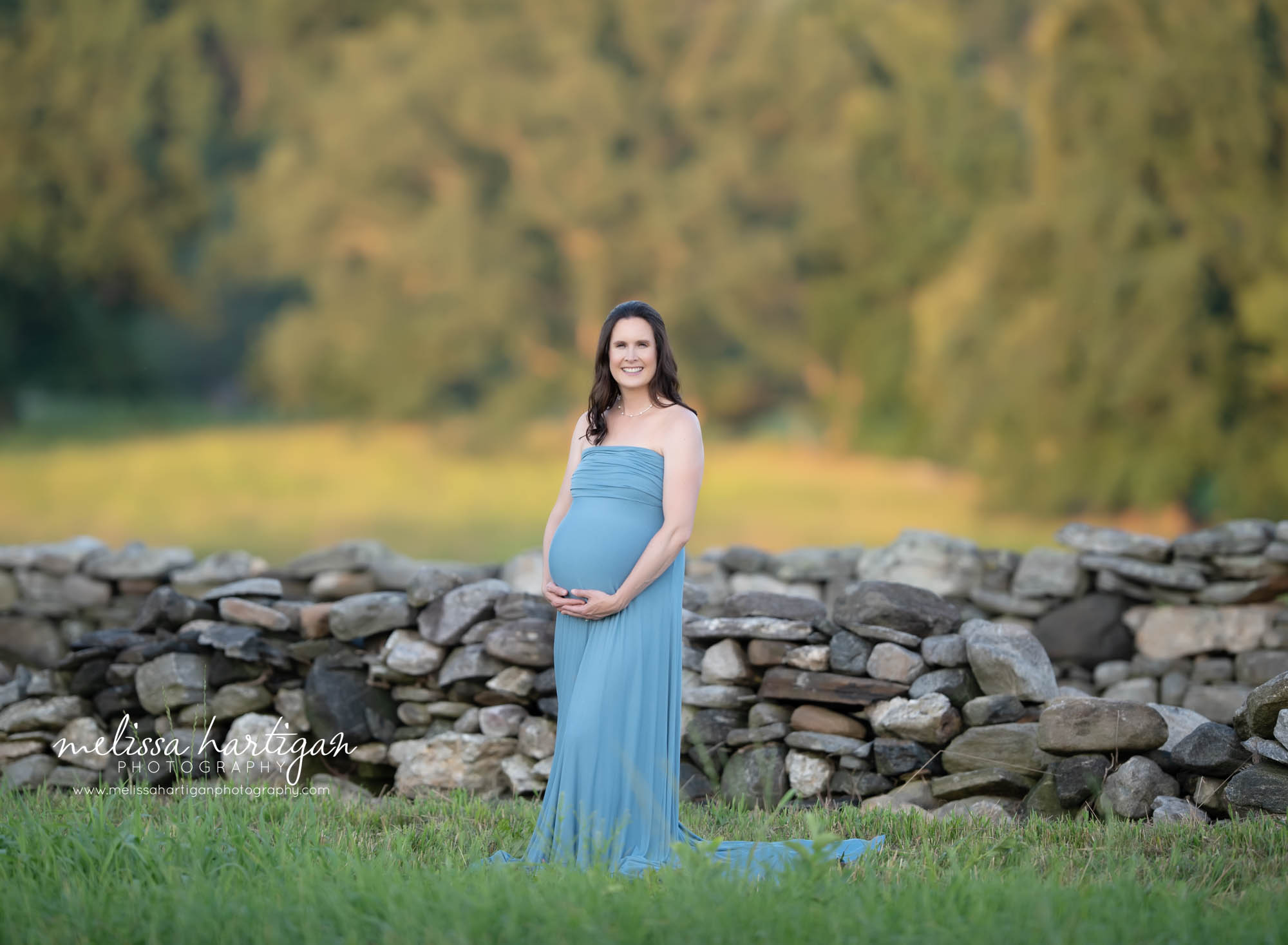 pregnant mother holding baby bump wearing long blue strapless maternity dress CT