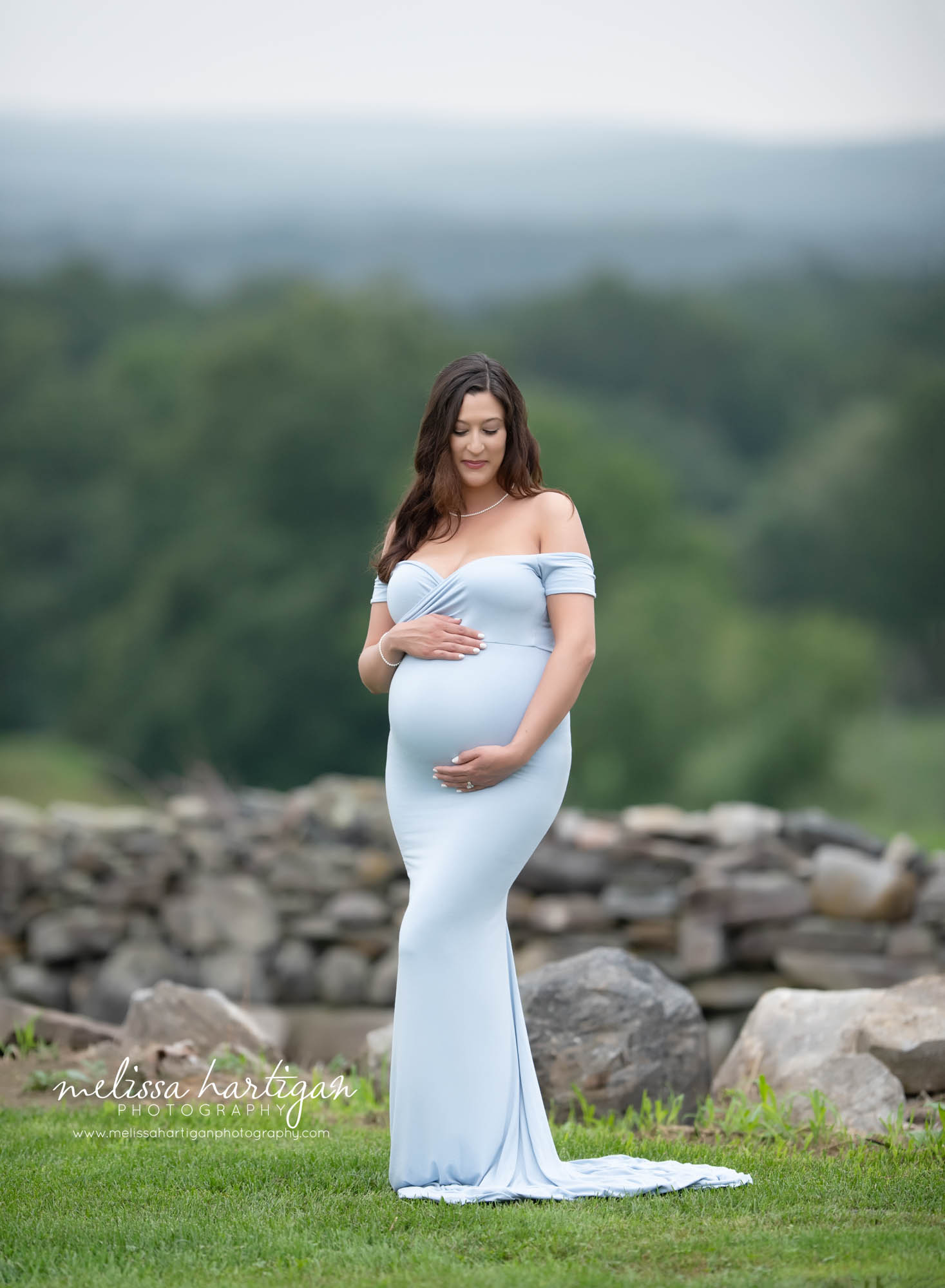 pregnant mom to be holding baby belly wearing light blue long form fitted dress with sleeves Connecticut maternity photography
