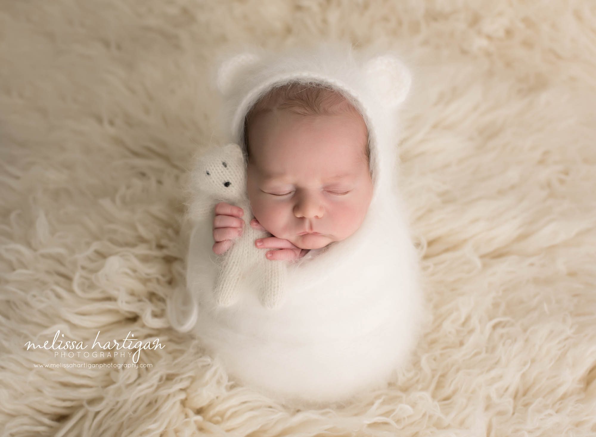 newborn baby boy posed in white cream knitted wrap with matching knitted white teddy bear and bear bonnet Connecticut newborn photography