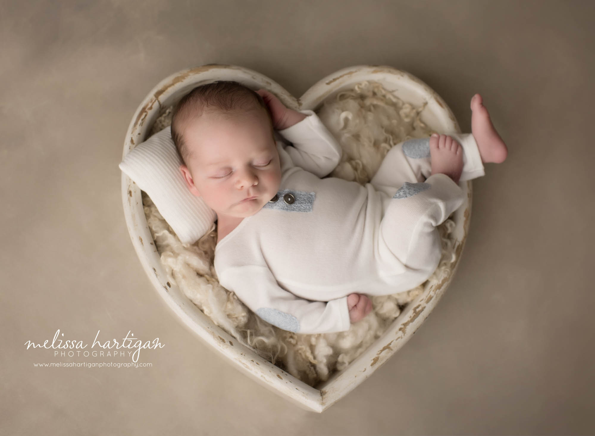newborn baby boy wearing cream colored outfit posed in cream colored bowl