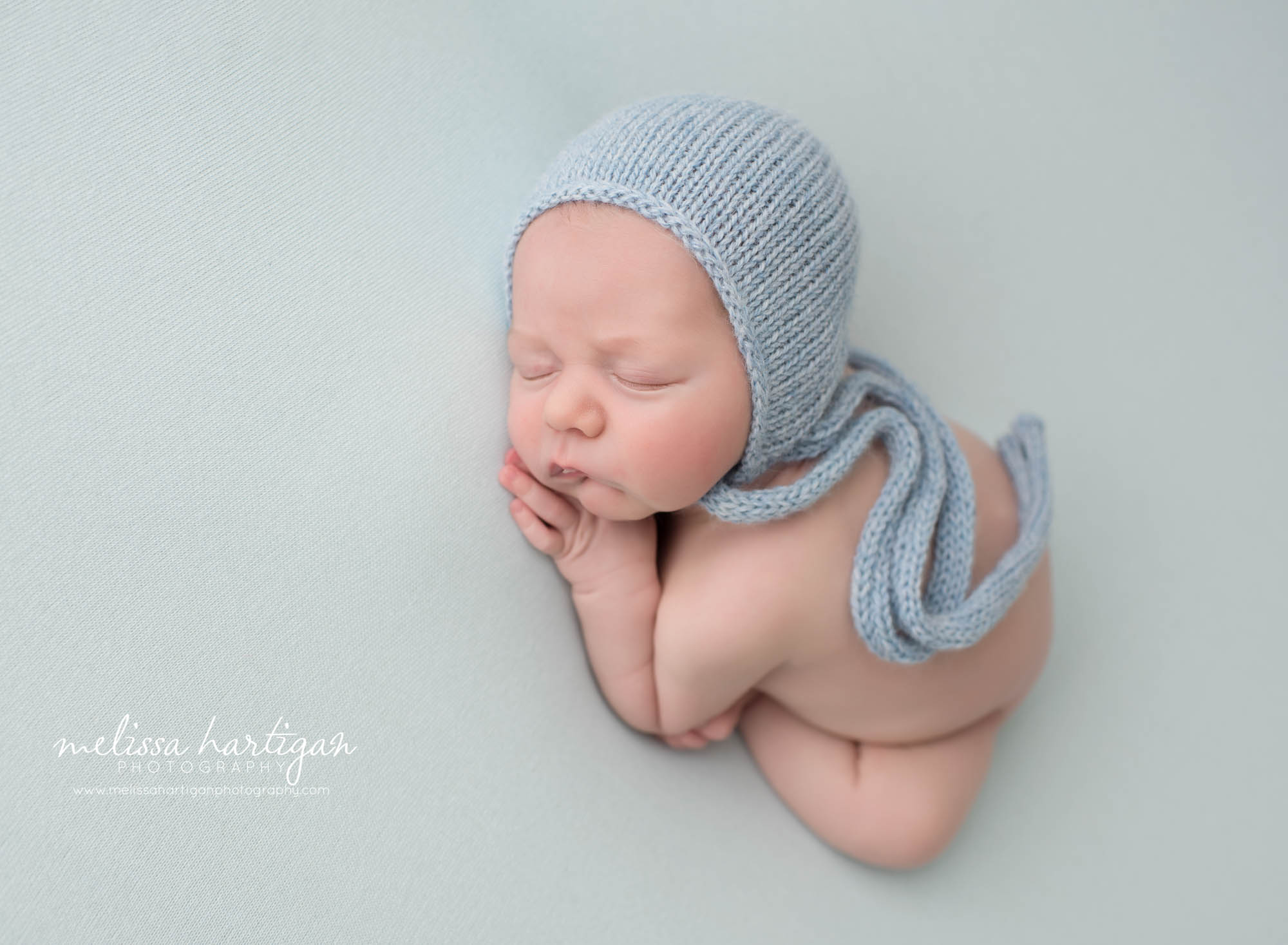 newborn baby boy posed on side wearing blue knitted bonnet newborn photographer CT