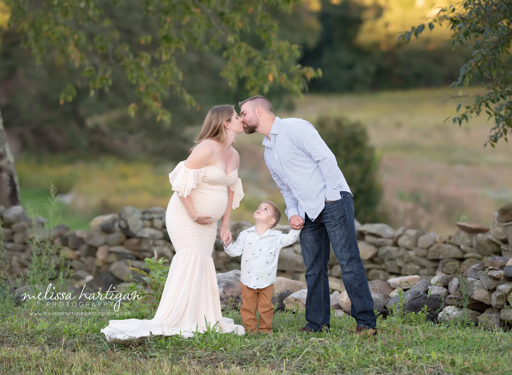 mom kissing dad holding sons hands in family maternity photography pose CT maternity Photography