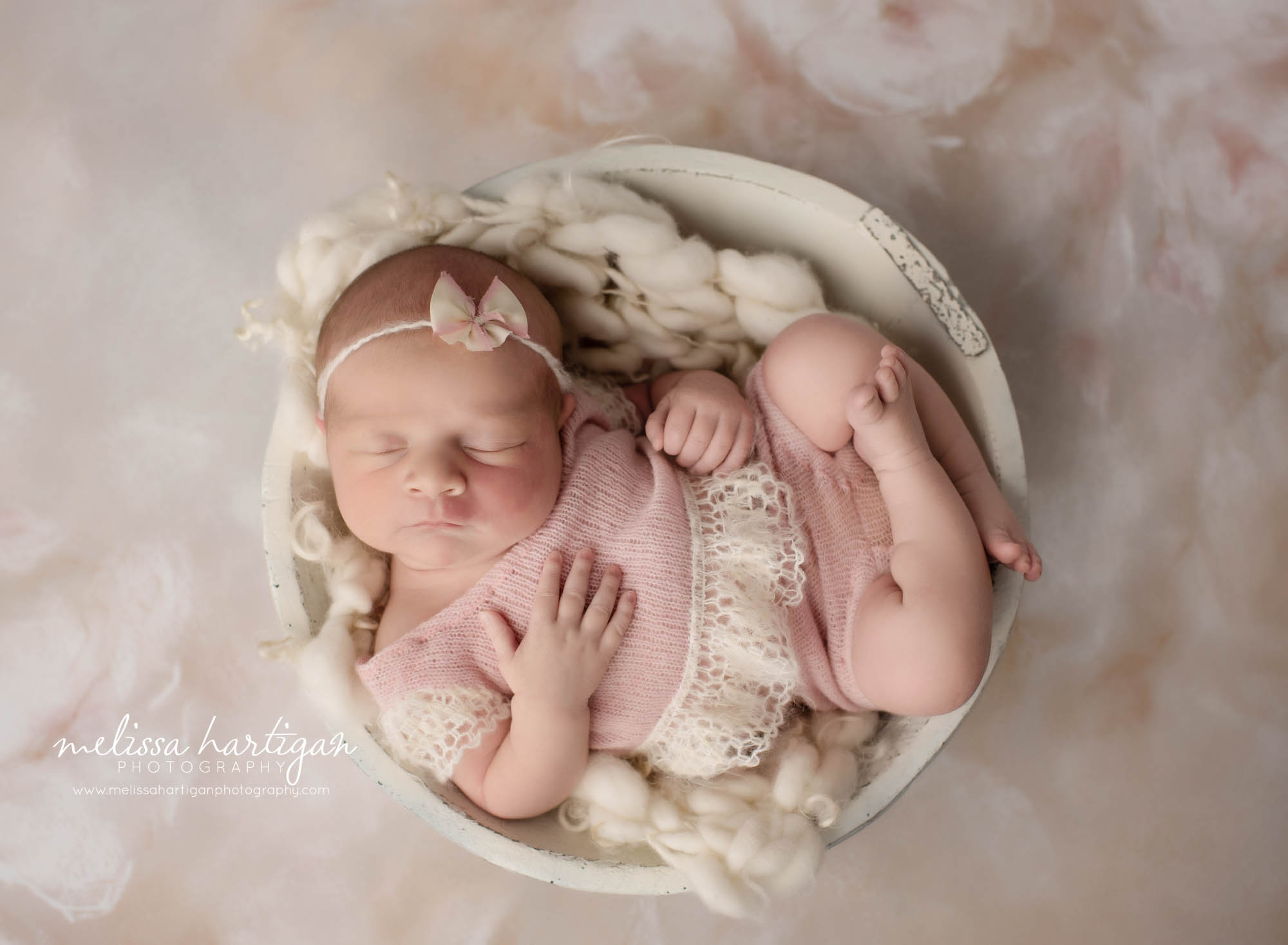 newborn baby girl ppsed in cream bowl wearing pink and cream lace outfit