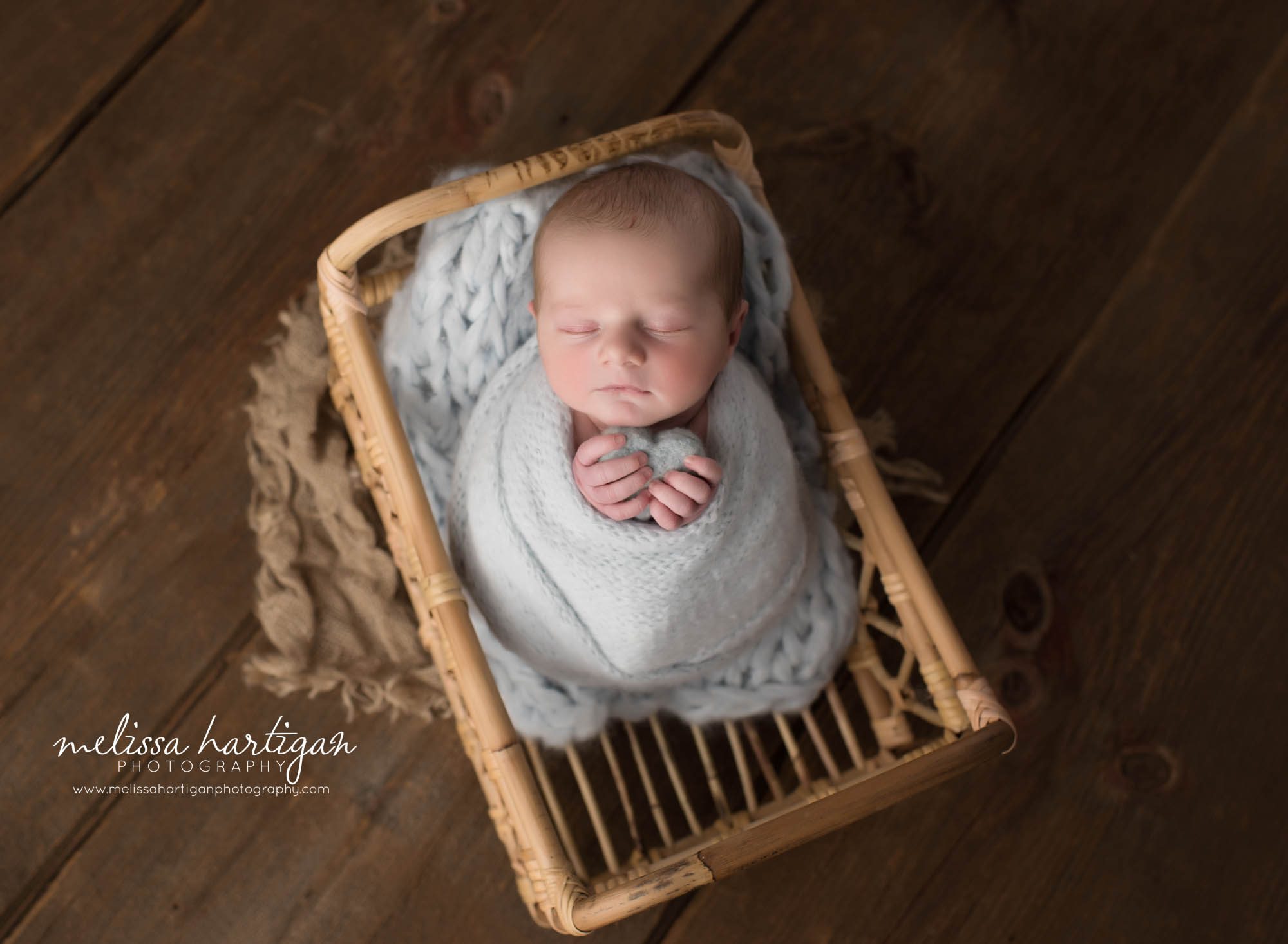 newborn baby boy wrapped in light blue knit wrap posed in basket with light blue felted heart prop newborn photography Connecticut