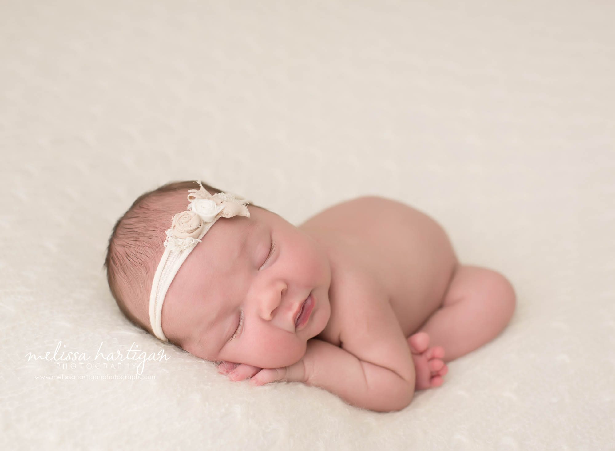 newborn baby girl posed modified taco pose wearing white headband
