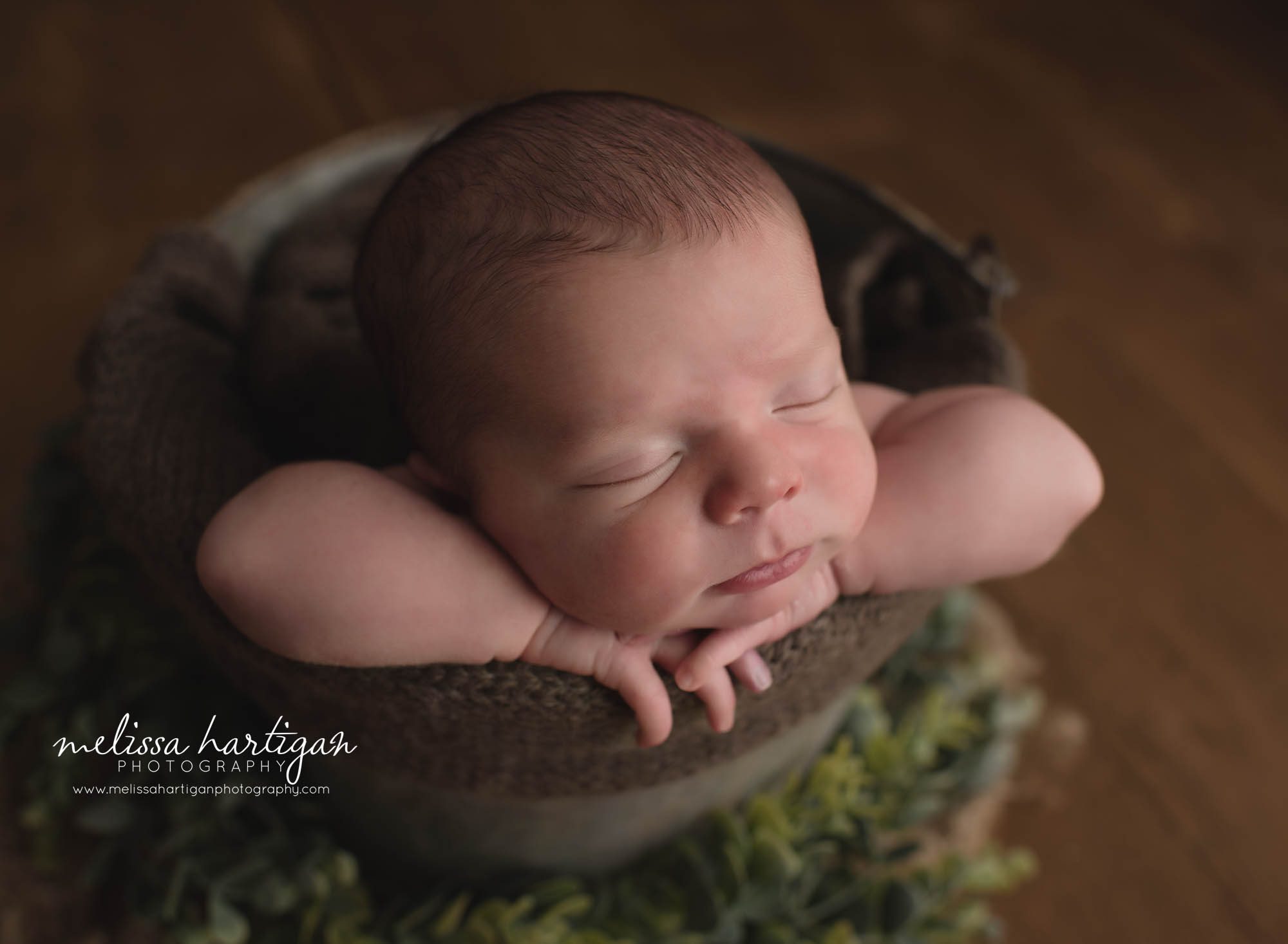 newborn baby boy posed in bucket captured from the side sleeping peacefully