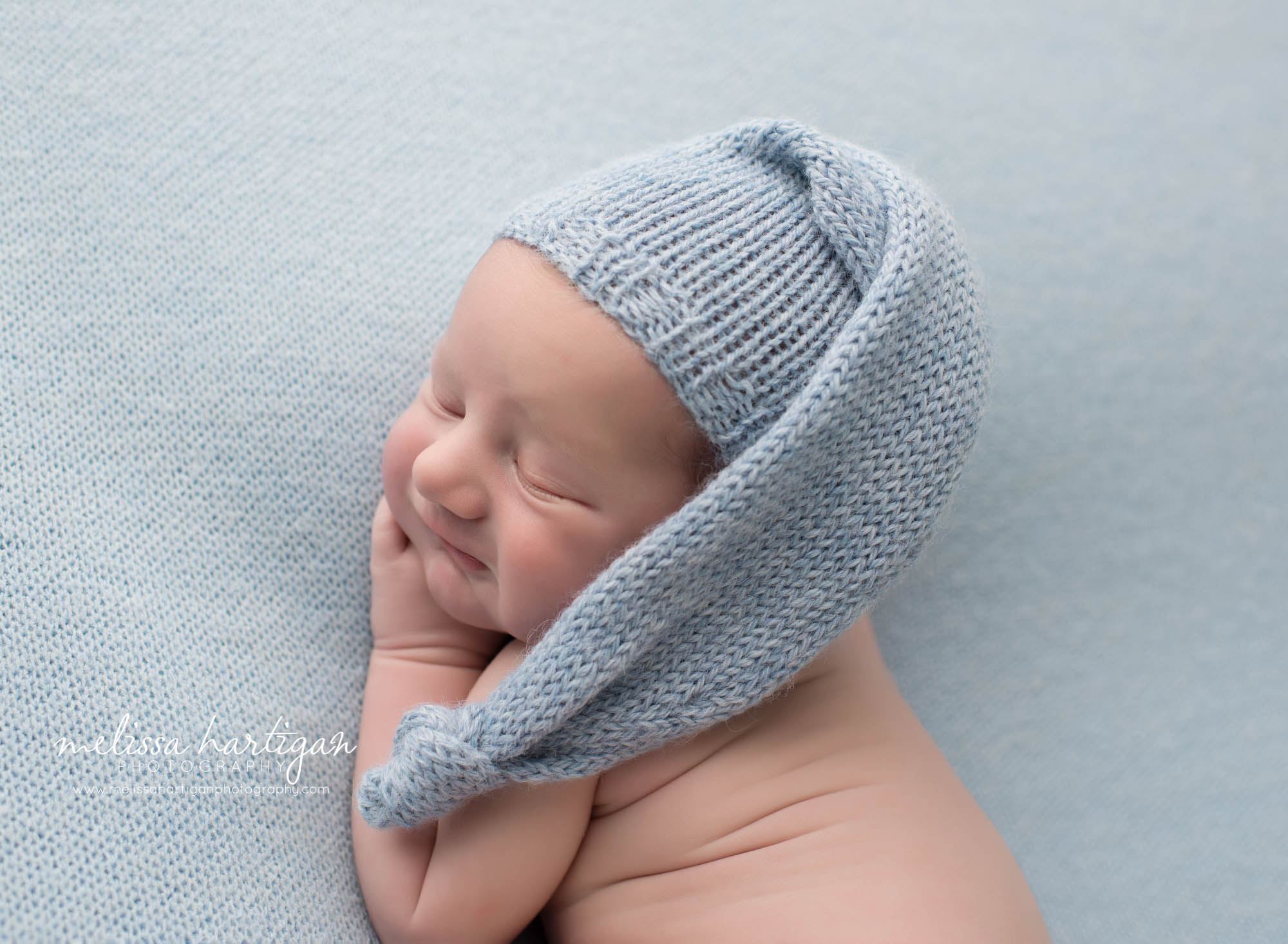 newborn baby boy posed on side wearing light blue sleepy cap CT newborn photographer