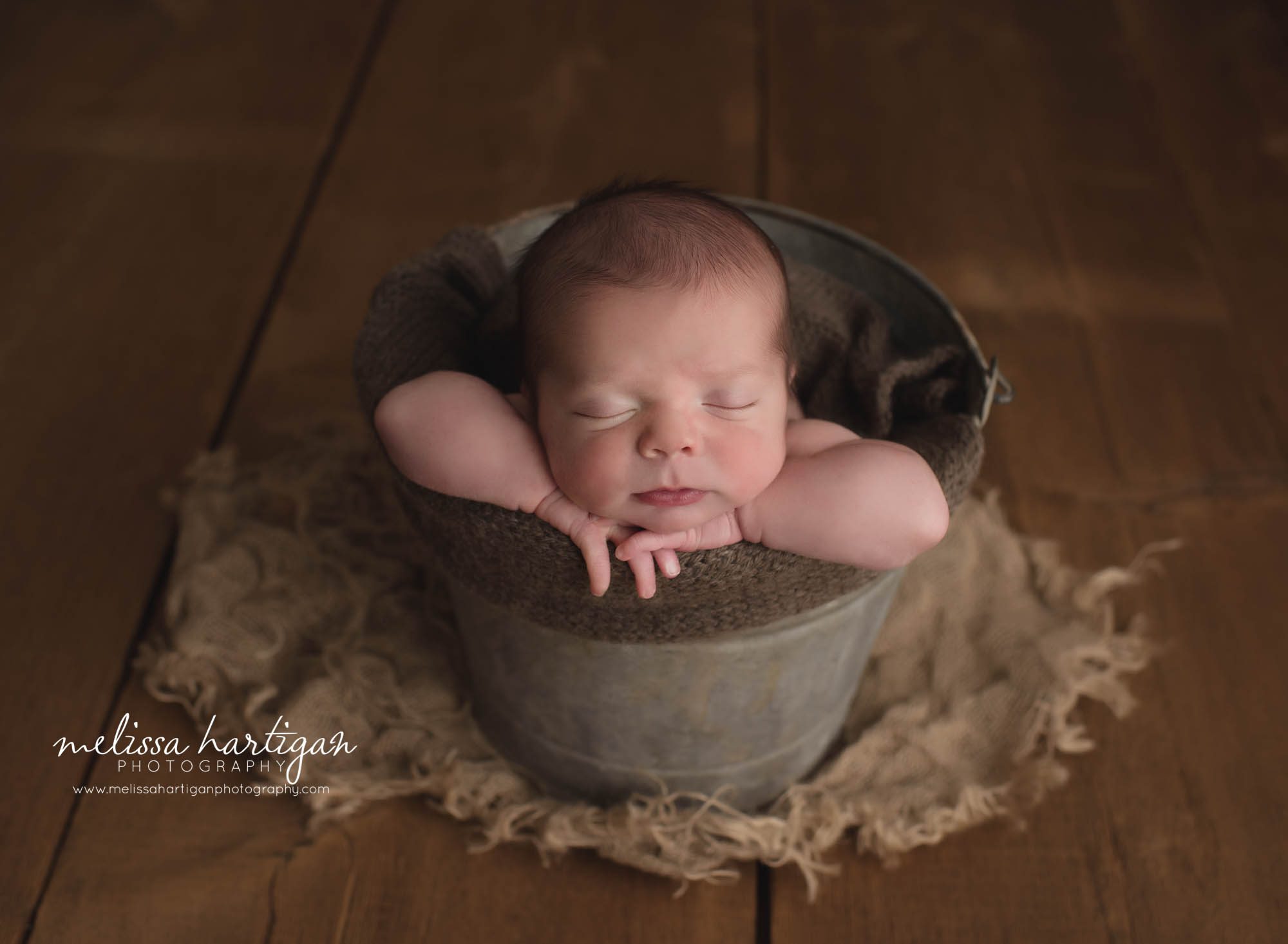 newborn baby boy posed in bucket with brown layer and green tone wrap middlesex county newborn photography