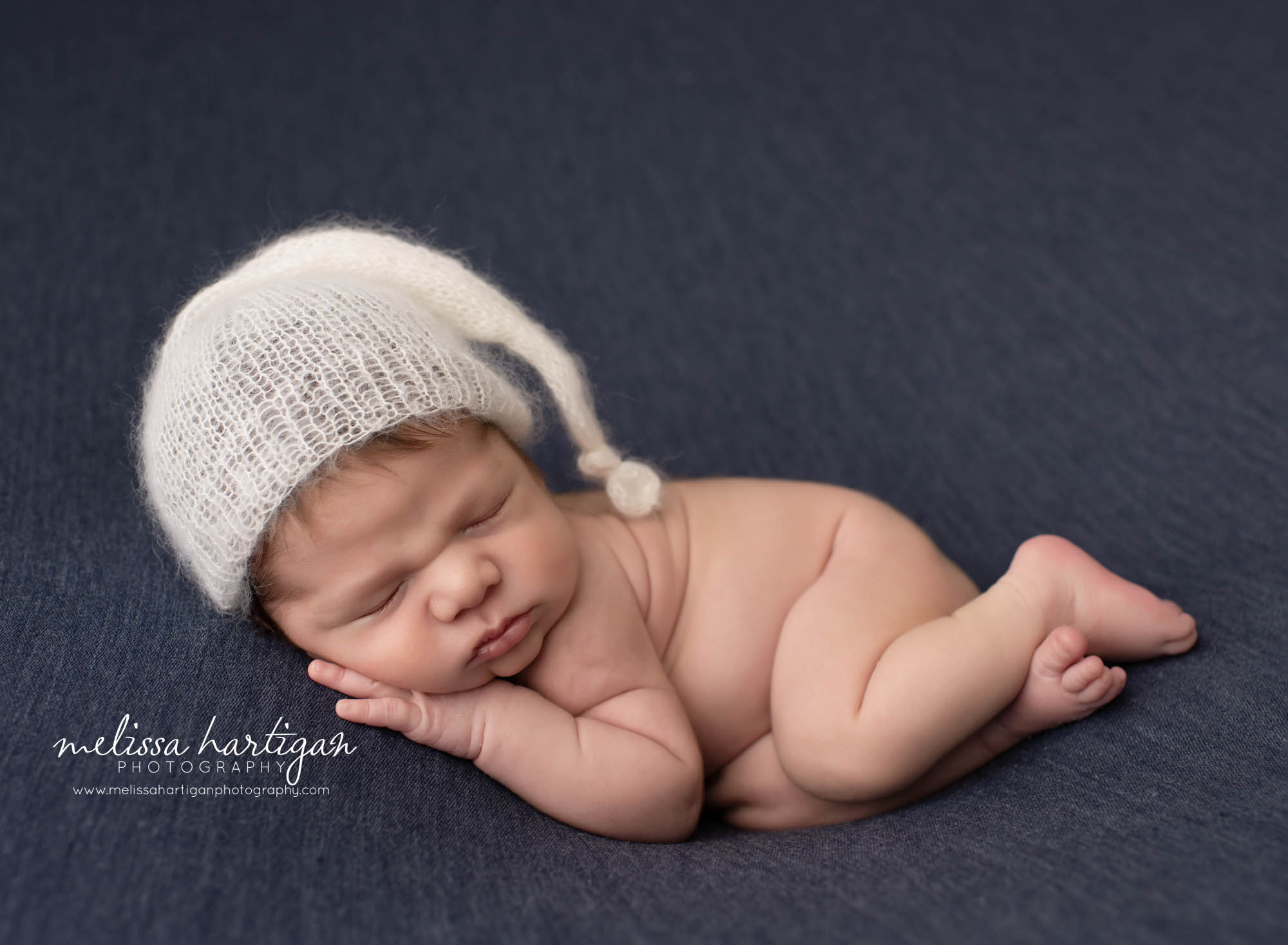 newbonr baby boy posed on side sleeping wearing knitted sleepy cap