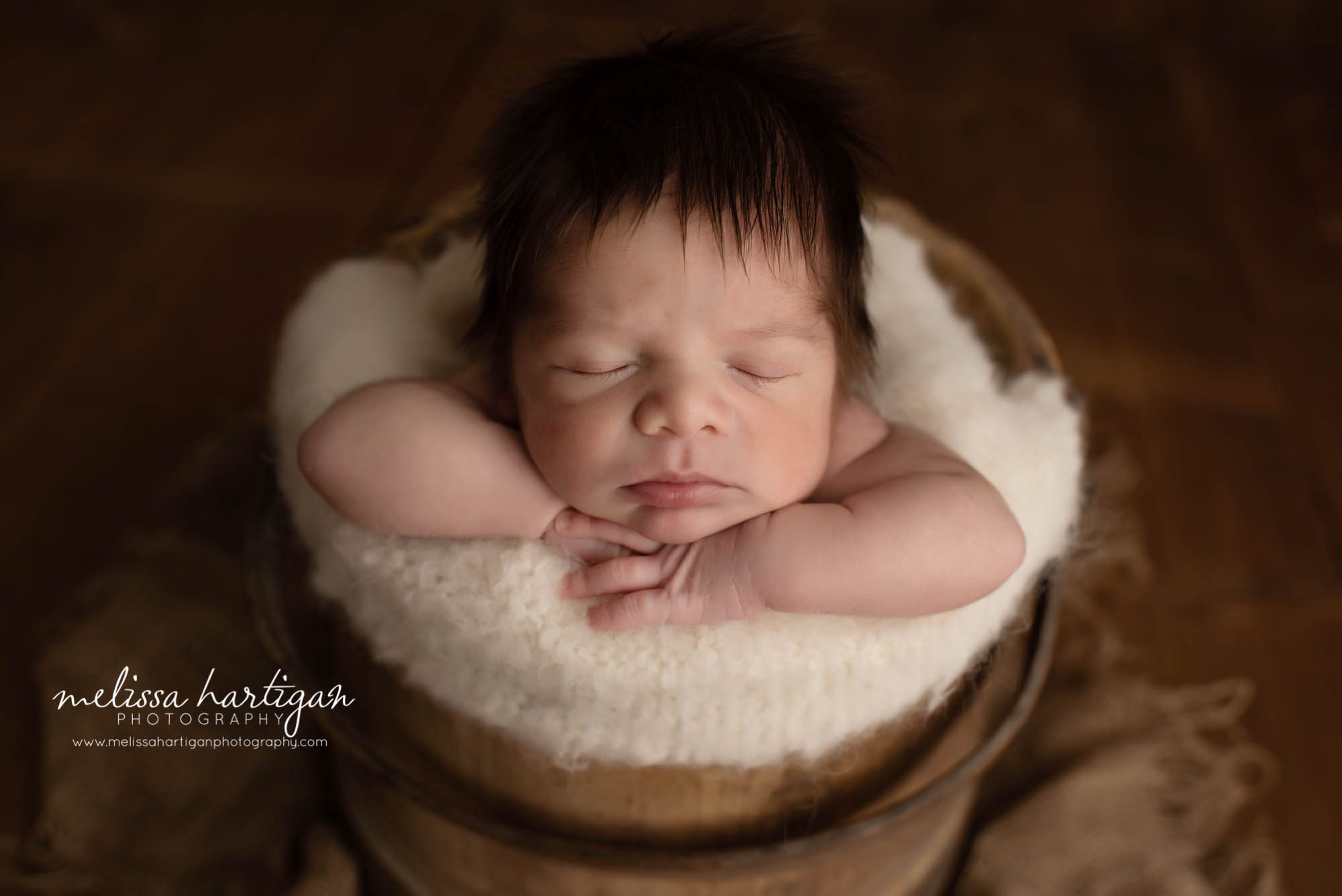newborn baby boy posed in wooden barrel bucket with cream layer baby boy with head full of hair