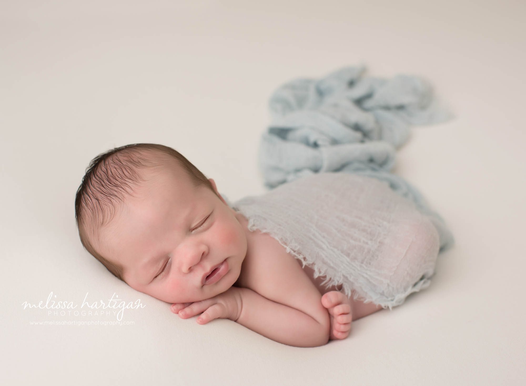 newborn baby boy posed modified taco loose with light blue wrap draped over backside suffield ct newborn photography